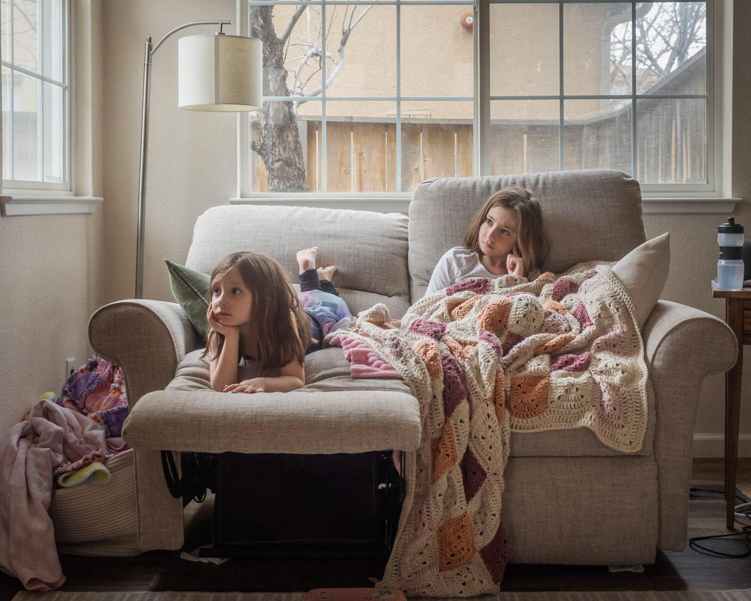 Two girls snuggle on a couch while watching TV