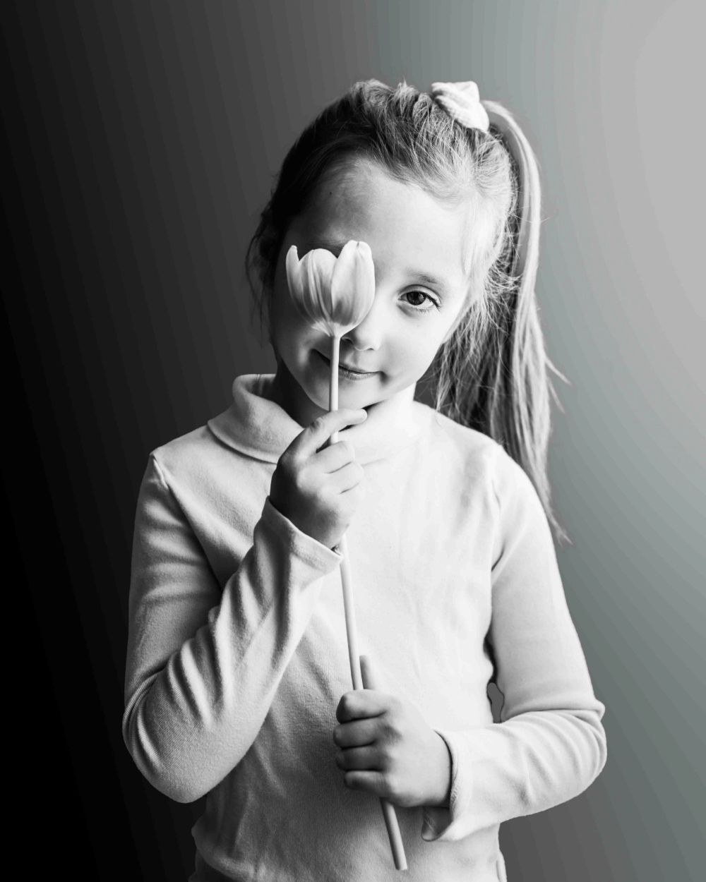 Portrait of young girl holding a flower over one eye