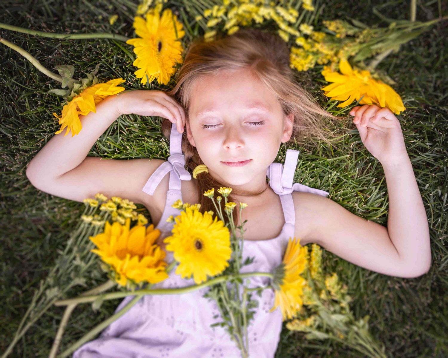 Girl laying down in grass with flowers strewn about