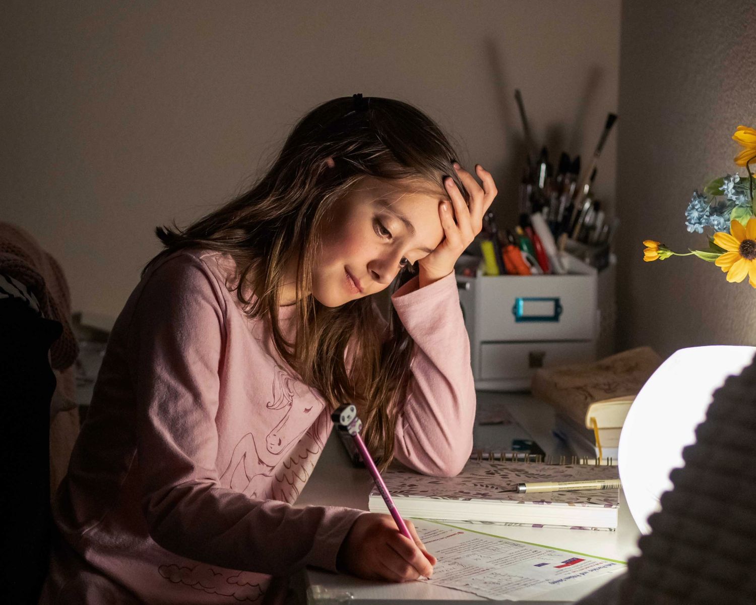 Young girl doing homework at desk in room