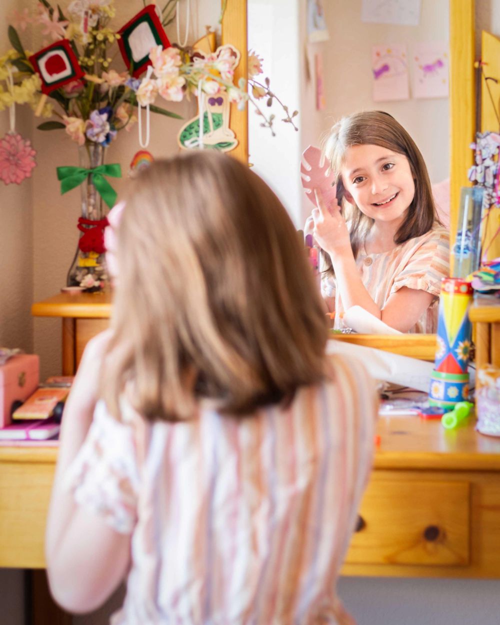 A girl does her hair while looking in a mirror