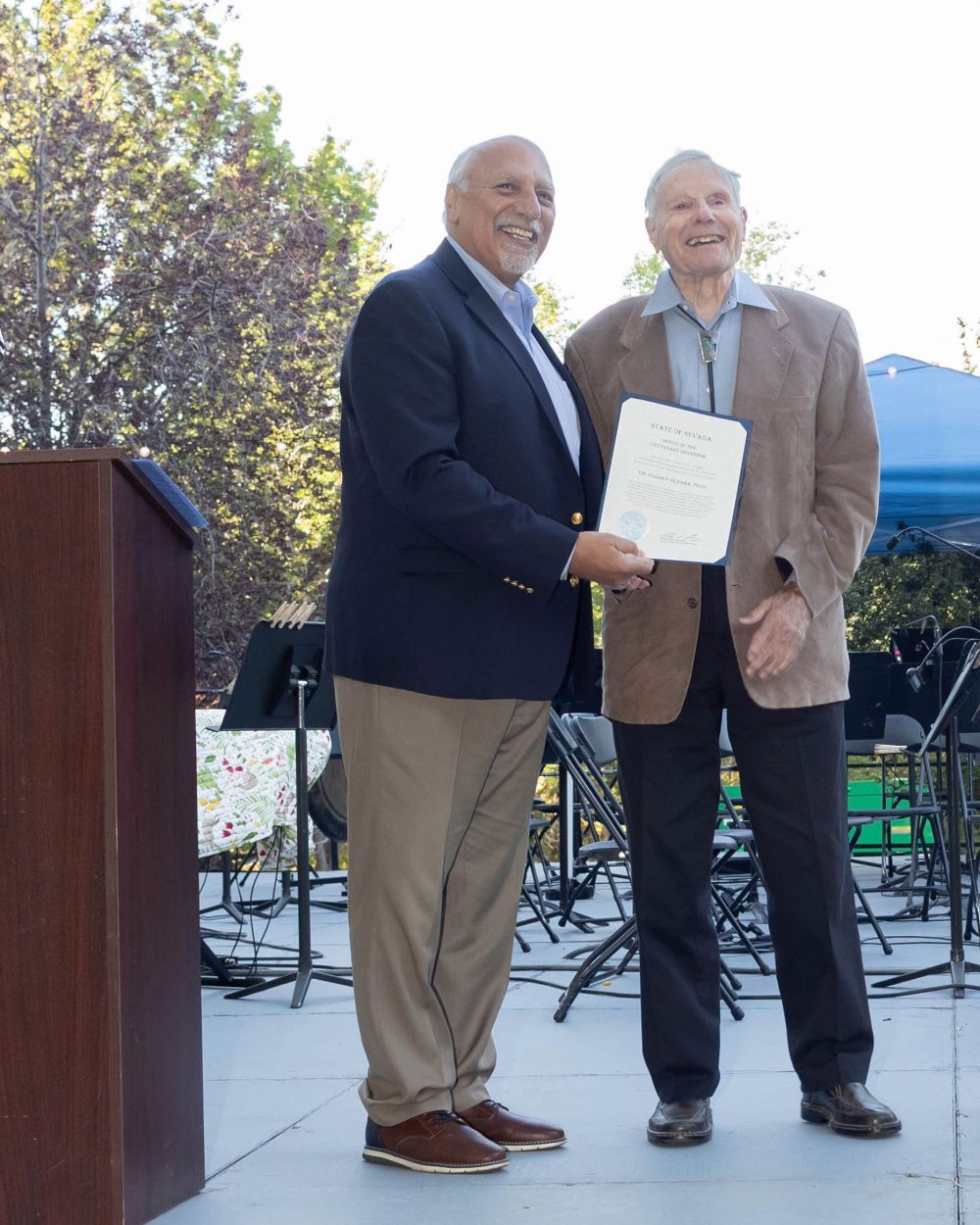A person awards another person on stage with a certificate