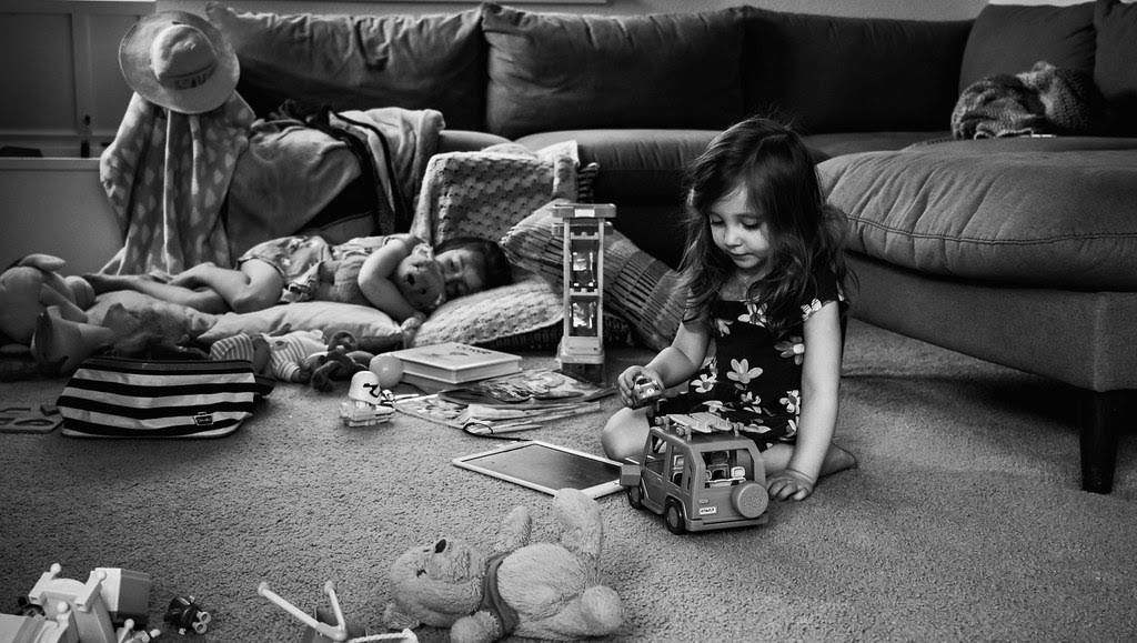 Girls sit on the floor in living room playing with toys