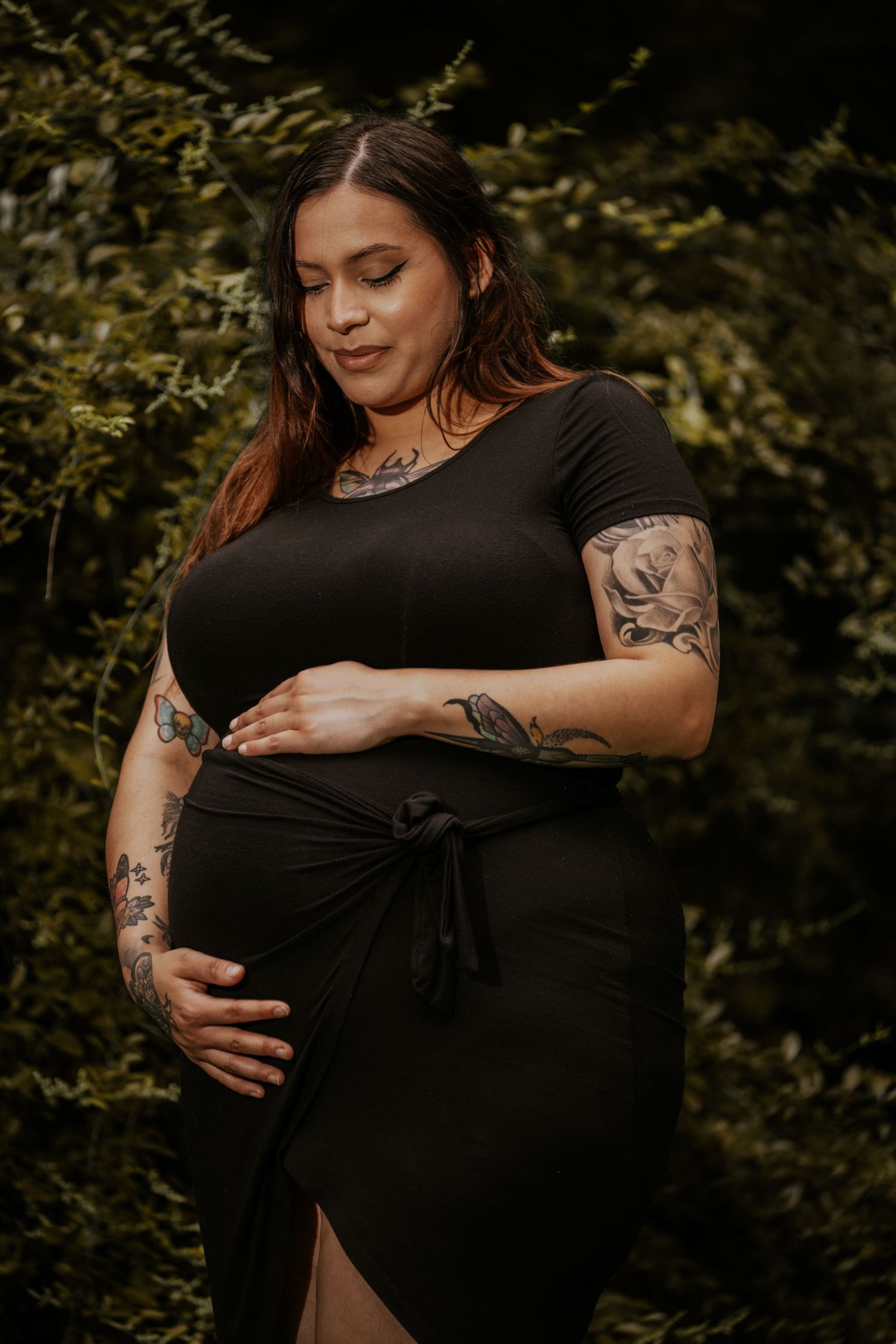 A series of maternity photos showing a woman in black dress with tattoos cradling her baby bump in an outdoor setting.