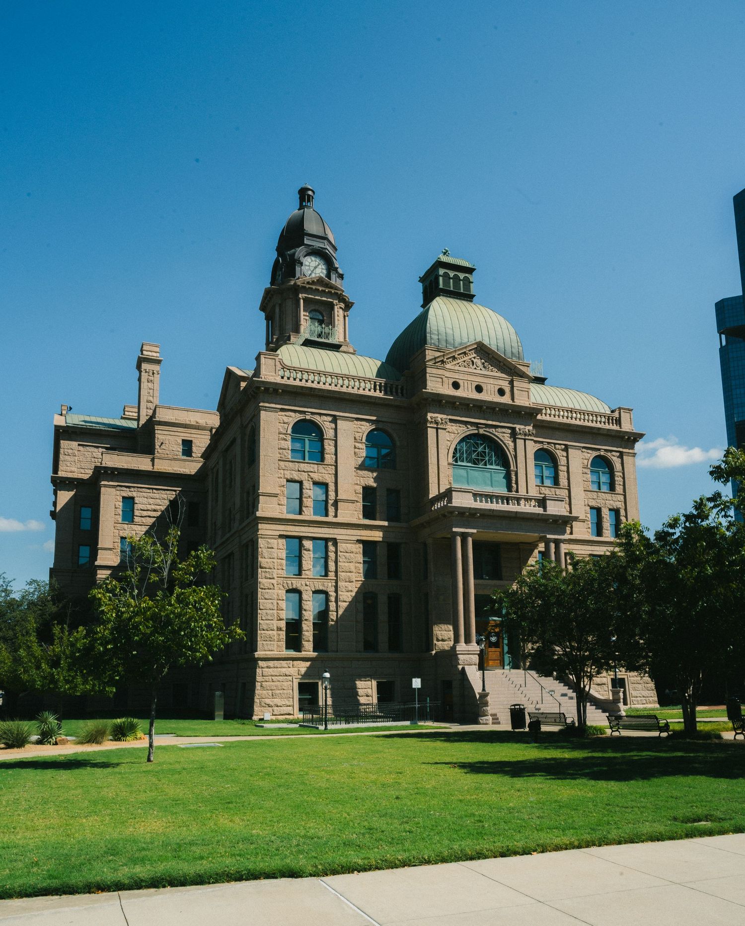 Historic Tarrant County Courthouse with ornate stone architecture, green dome, and clock tower under a clear blue sky in Fort Worth, Texas.