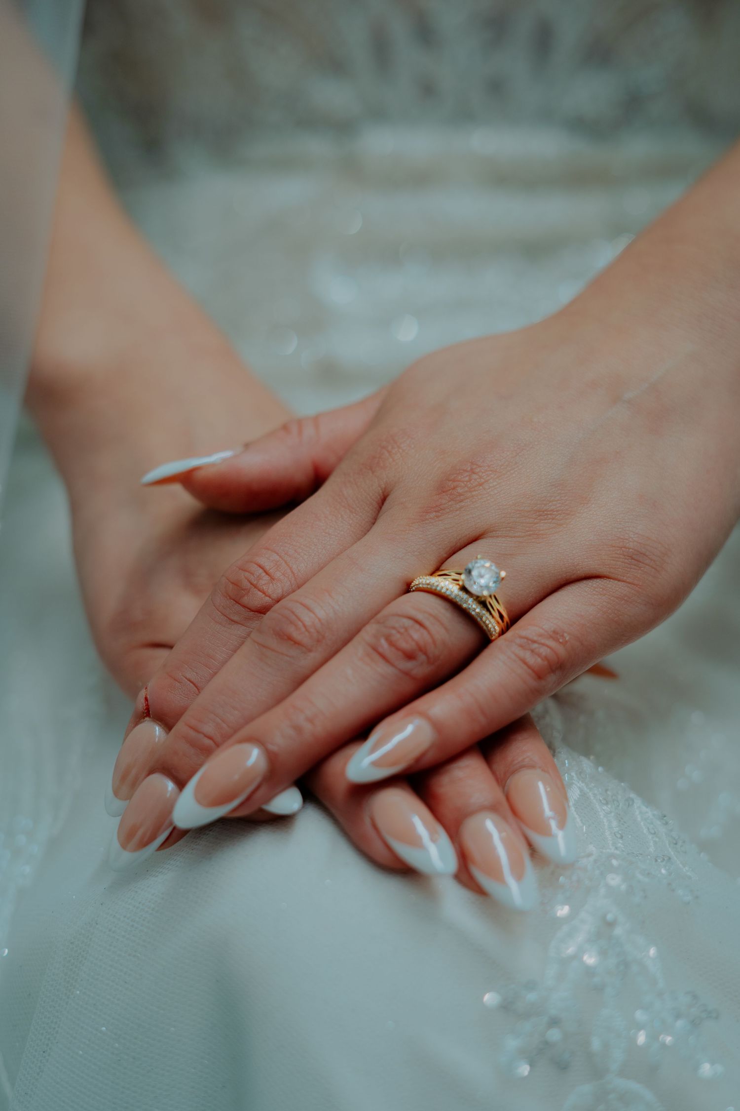 Close-up shots of hands with manicured nails wearing an engagement ring with sparkling diamonds.