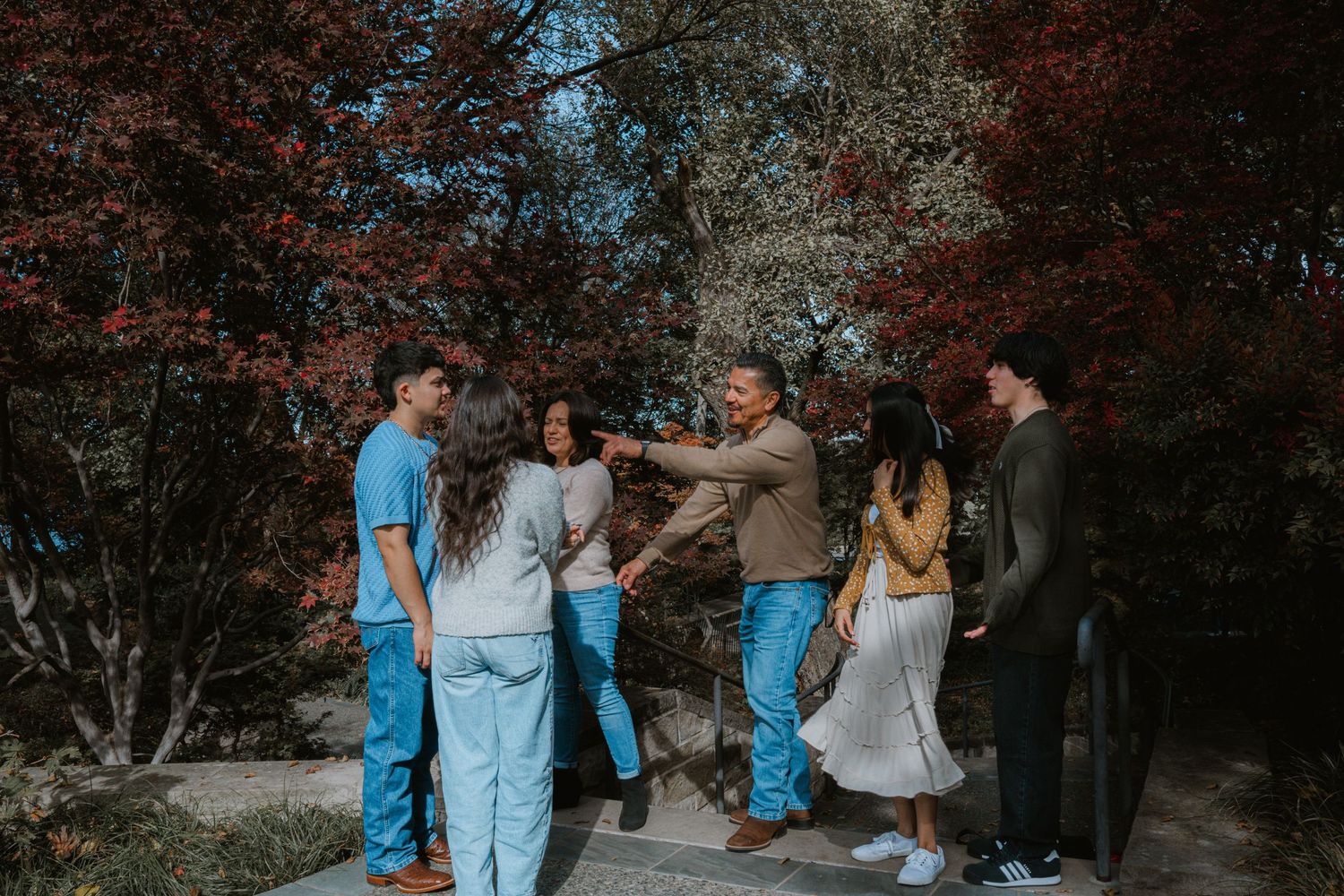 A group in coordinated blue and gray outfits walks together in a wooded outdoor setting during autumn.