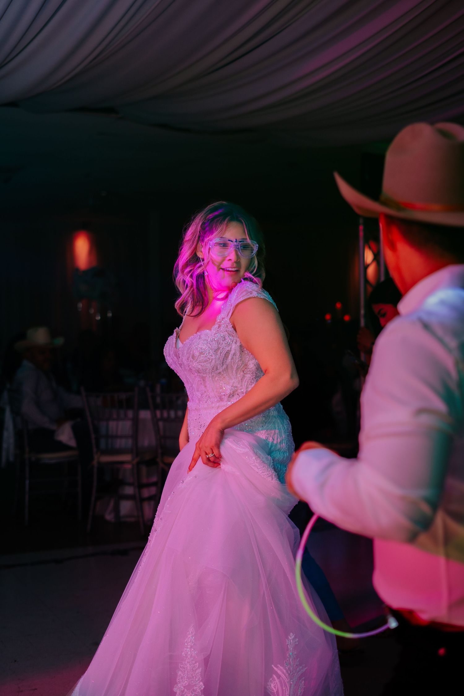 Wedding celebration on dance floor with colorful pink and blue lighting creating a festive atmosphere.