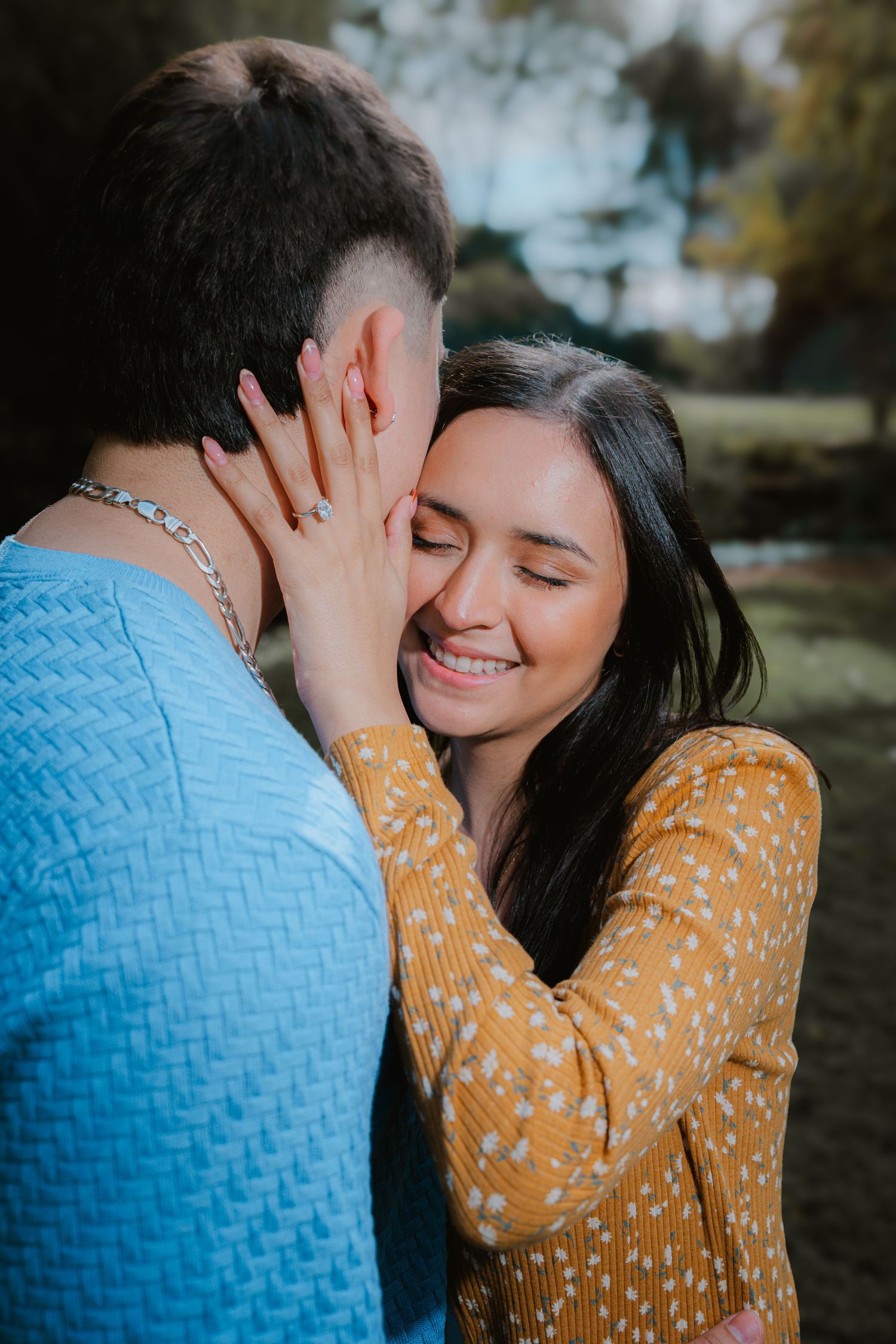 A tender moment captured between two people wearing blue and yellow outfits in an outdoor setting.