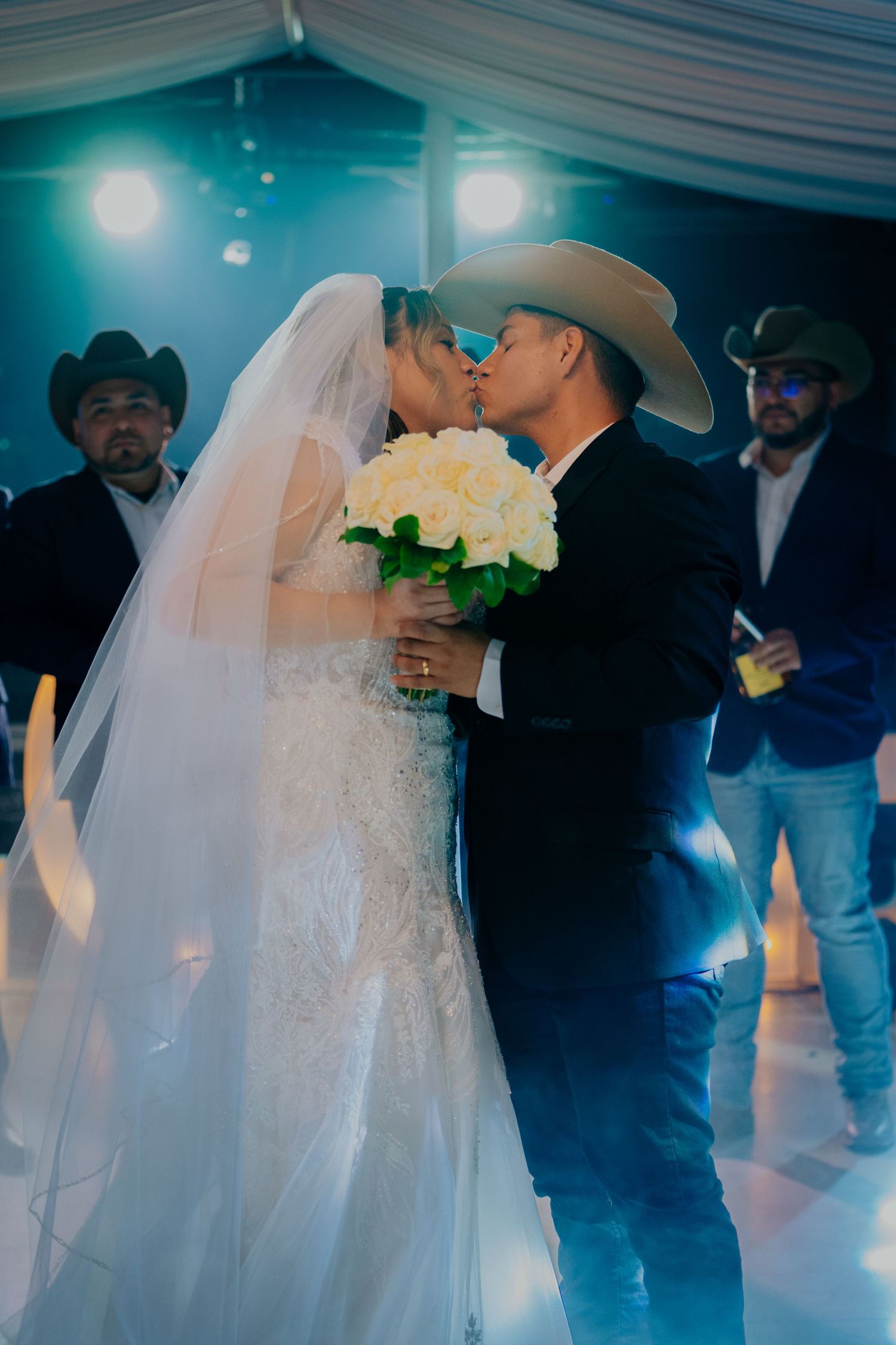Romantic first dance at a wedding reception with blue lighting and flowing white decor creating a dreamy atmosphere.