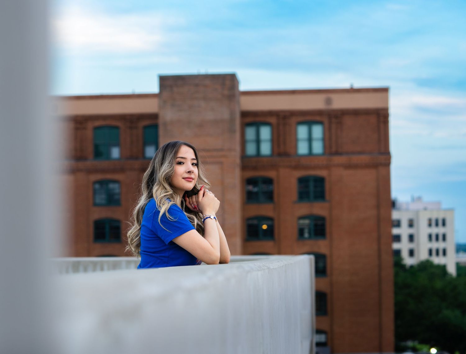 Urban rooftop photoshoot with modern architecture and blue sky backdrop.