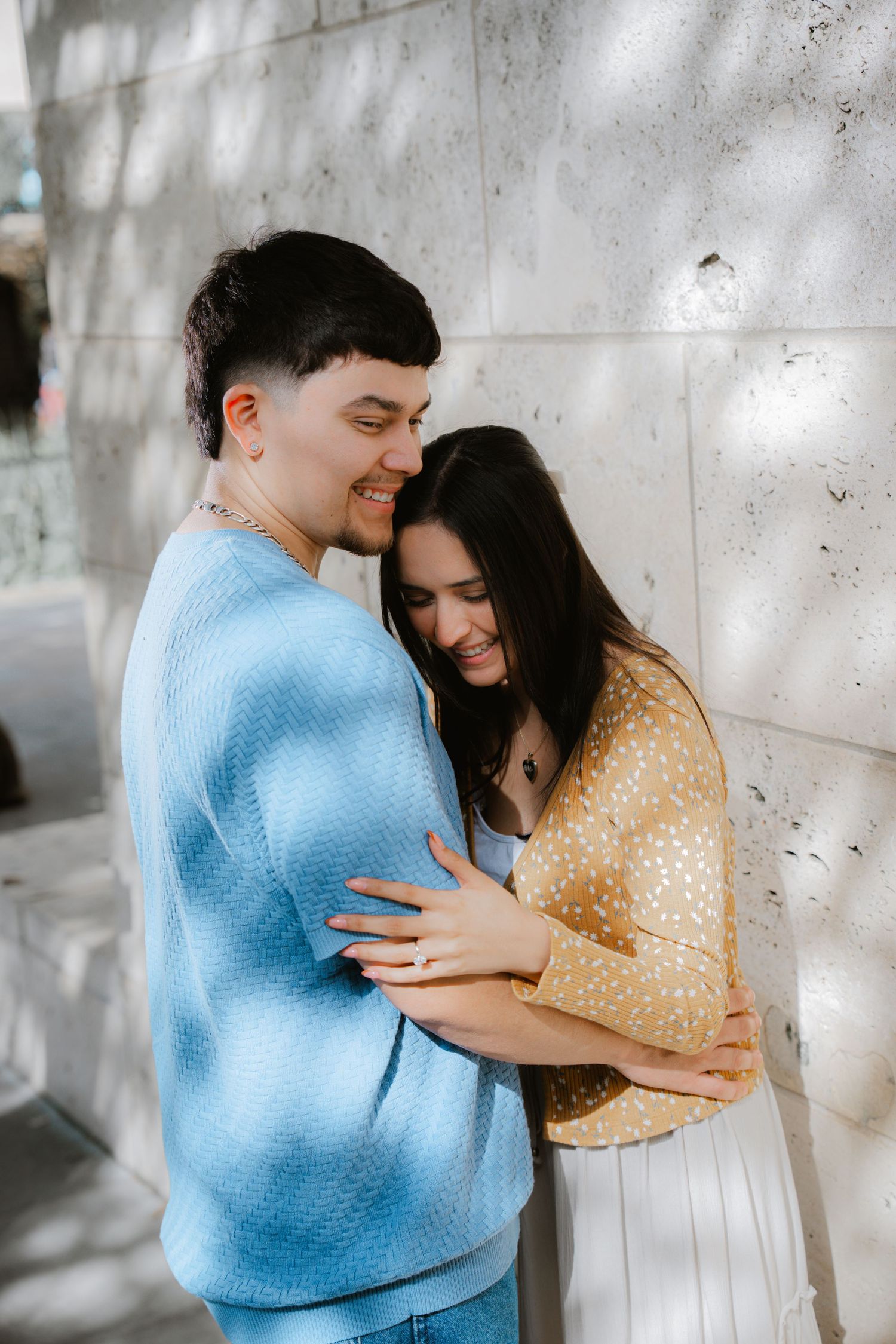 A romantic moment between two people in cozy sweaters against a concrete wall.