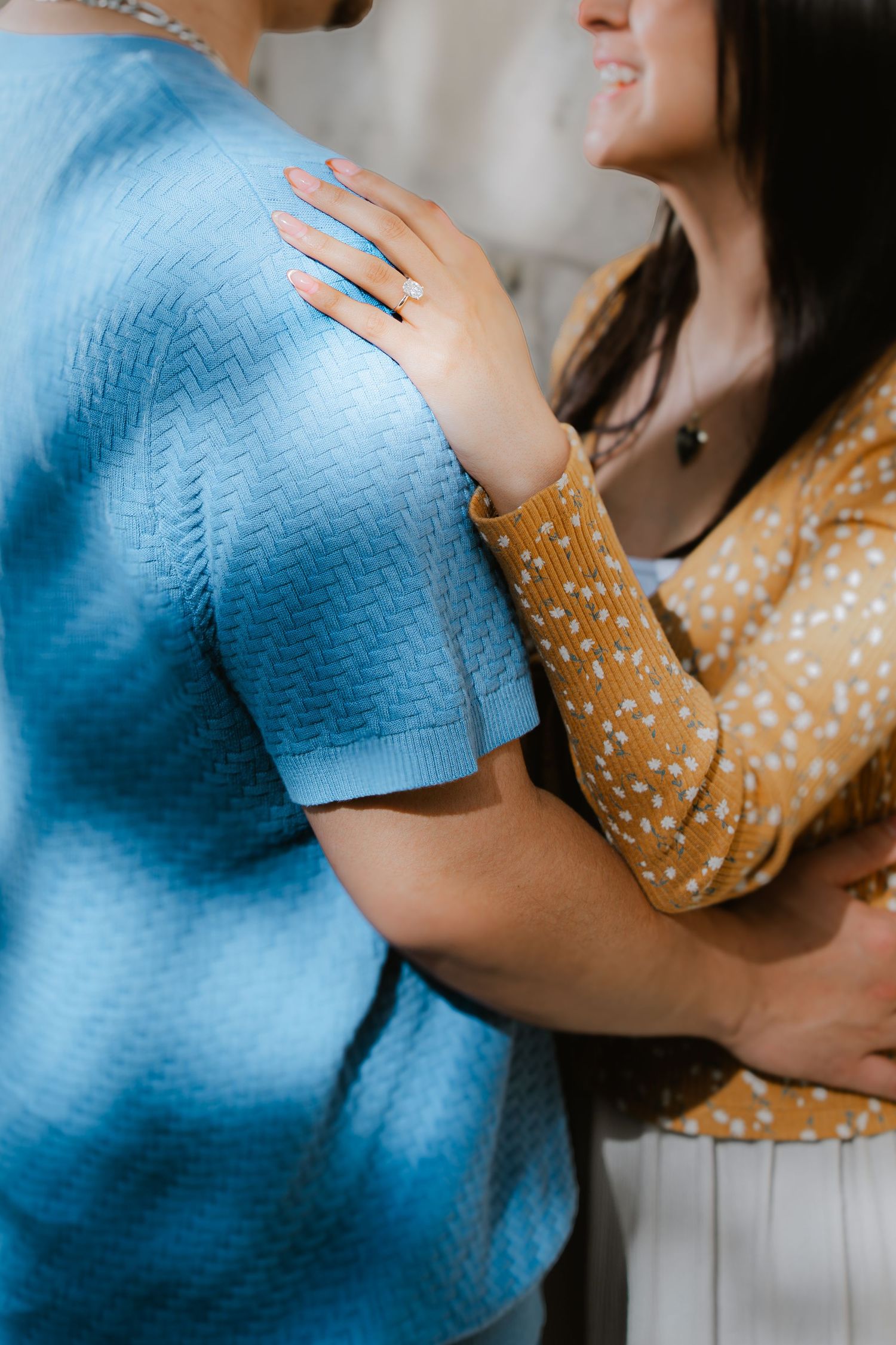 Close-up shot of an embrace between two people wearing blue and yellow polka dot clothing.