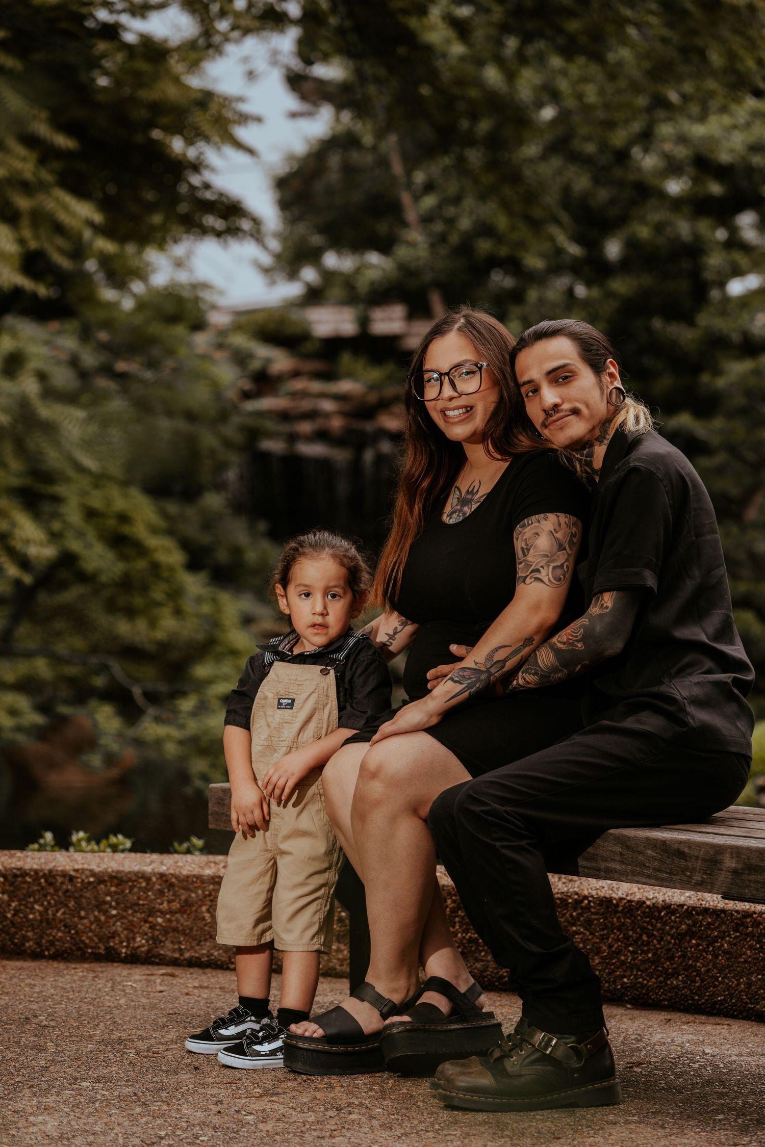 A family sits together on a stone wall in a park during golden hour.