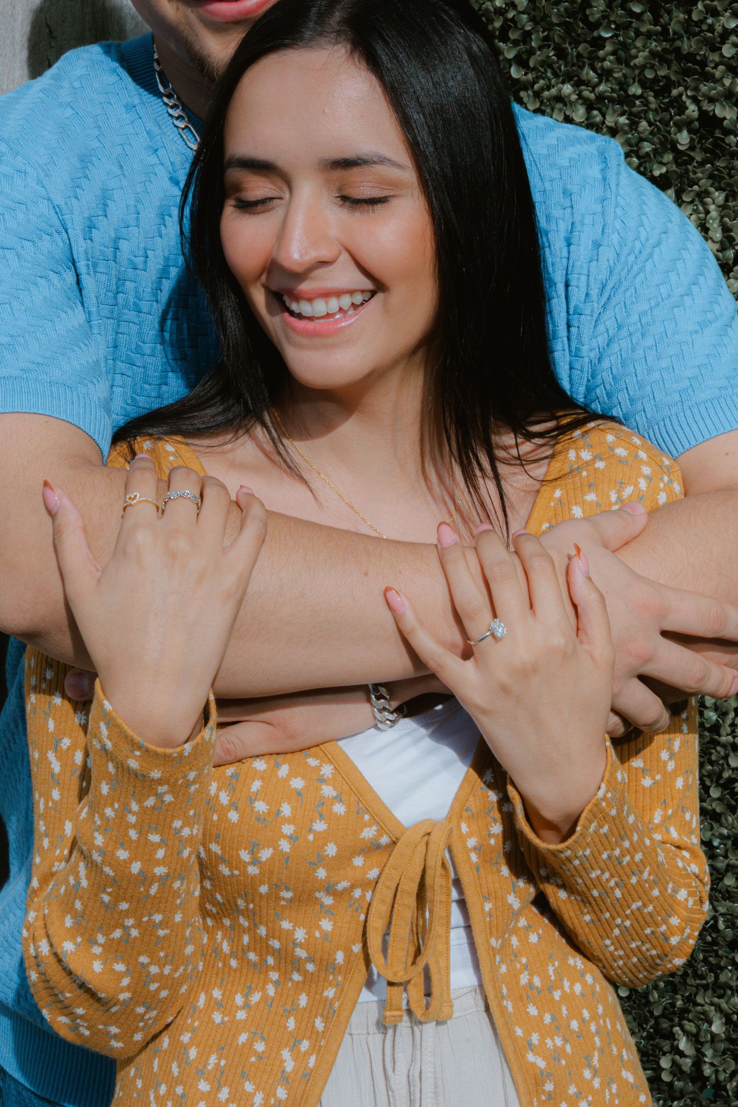 Close-up shot showing hands with a new engagement ring against a yellow polka dot dress.