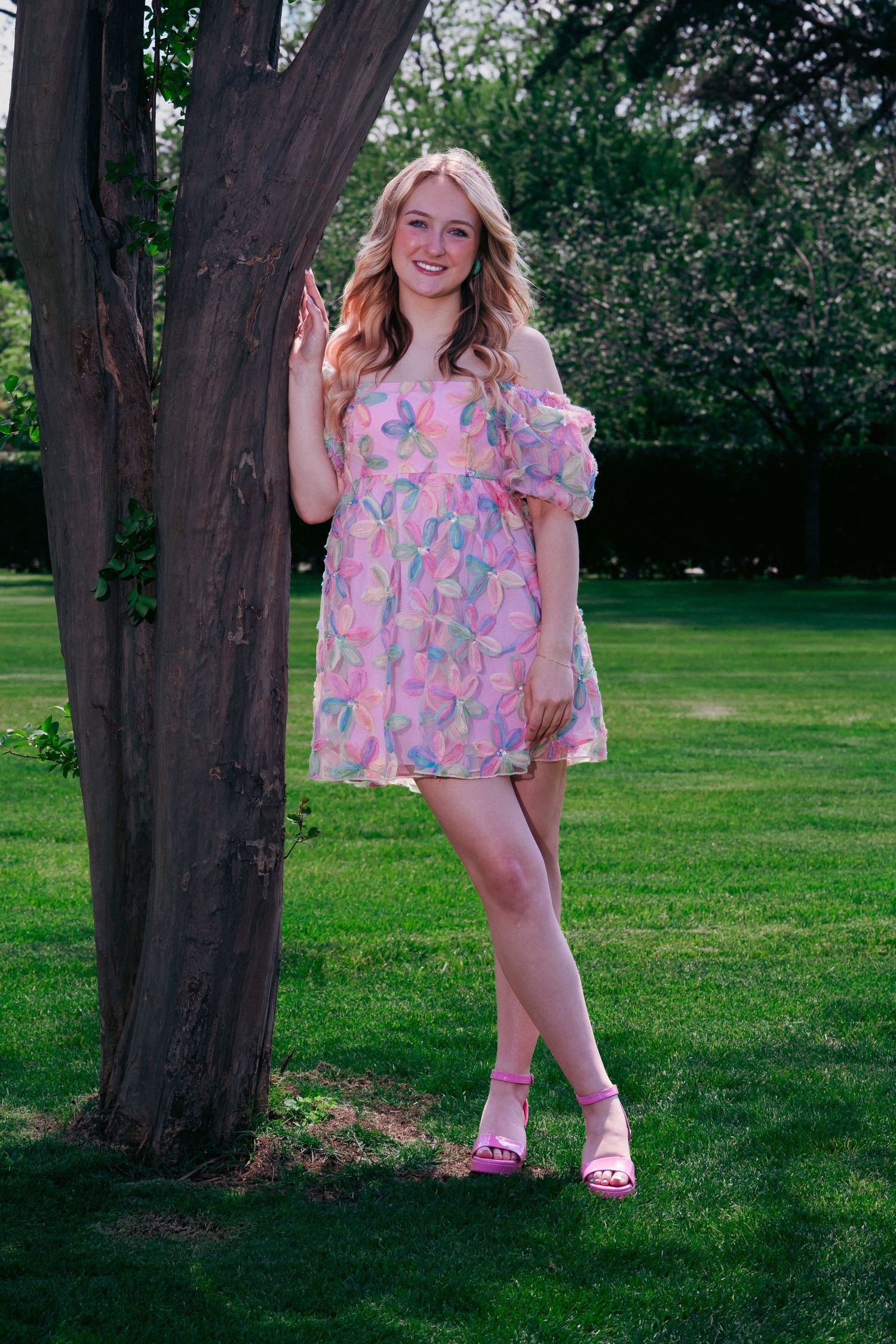 Pink floral dress photographed in a series of poses against a lush green park setting with mature trees.