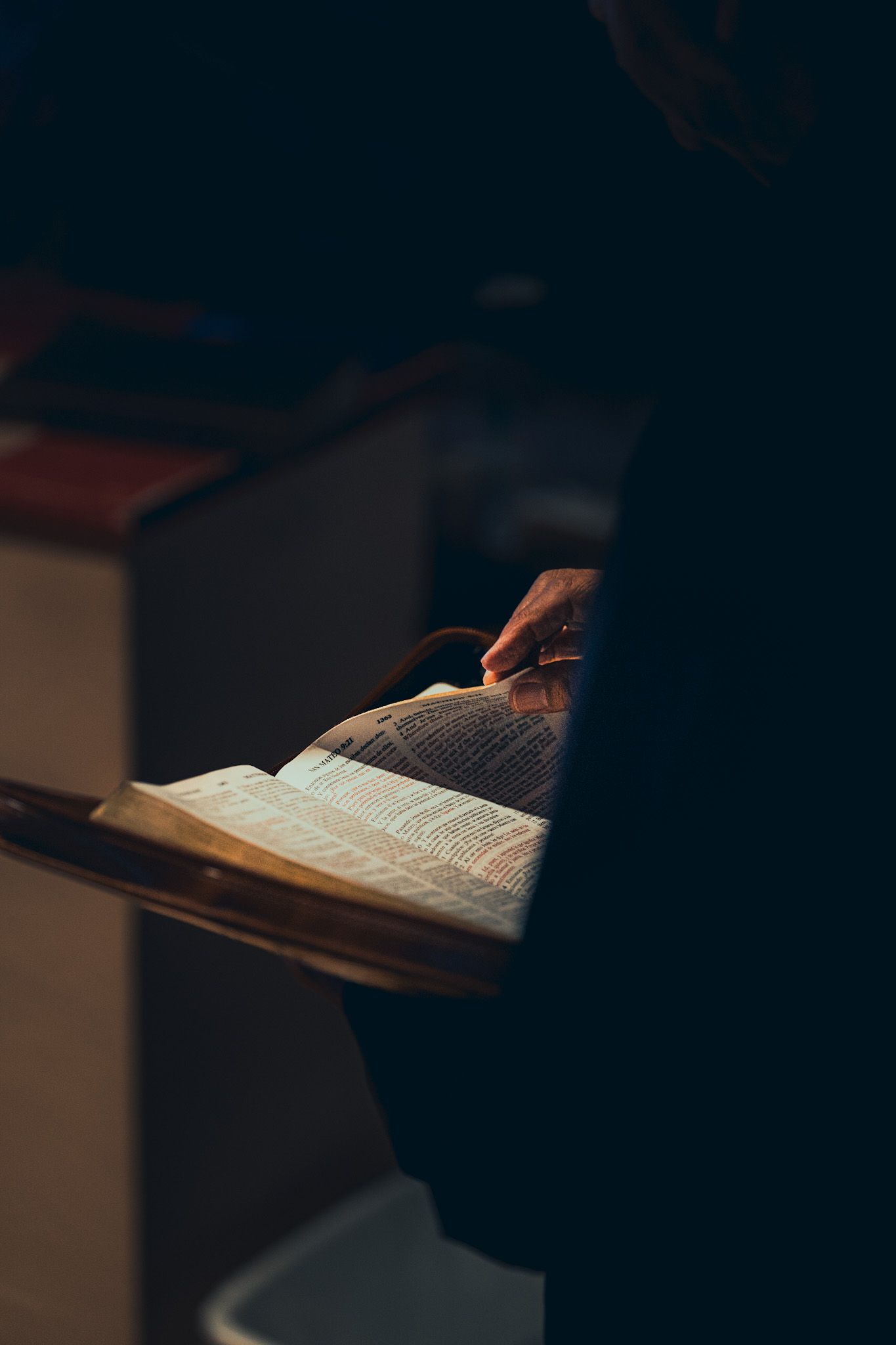 An open book illuminated in dramatic lighting against a dark background.