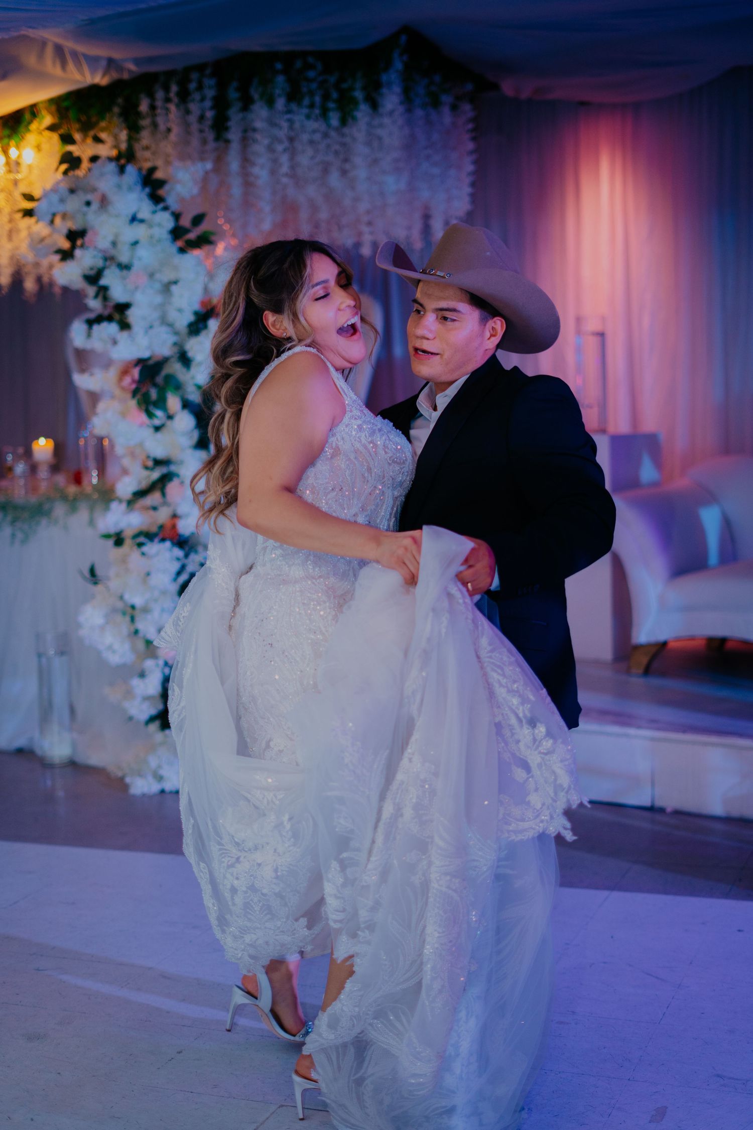 A romantic wedding dance sequence showing the groom dipping the bride in a beautifully lit purple reception venue.