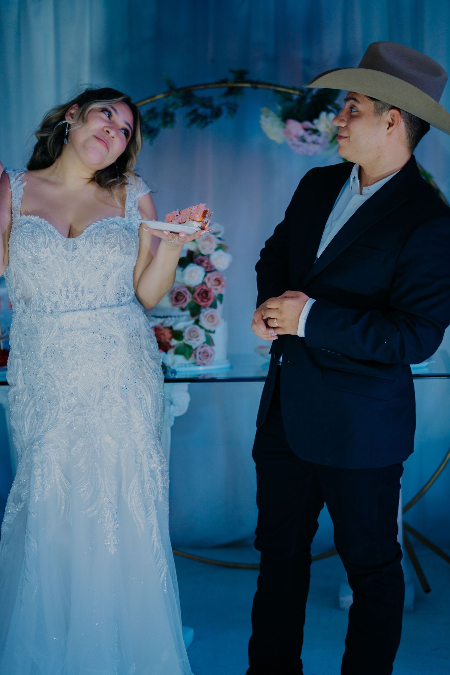 A couple in wedding attire dances together in a sequence of romantic poses with blue lighting in the background.
