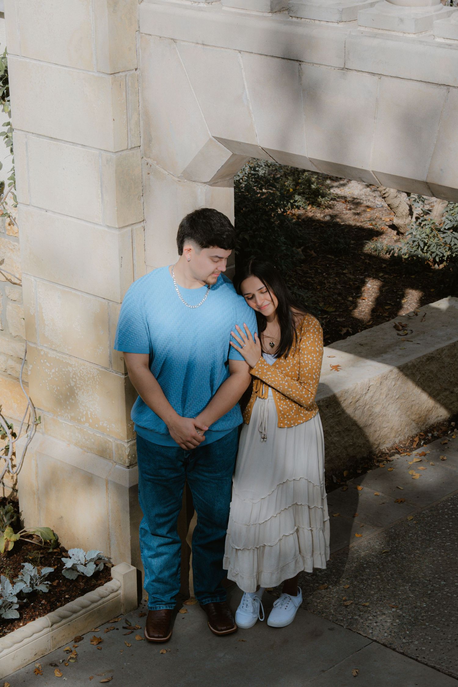 A romantic couple in casual attire share tender moments against a white wall in a series of intimate poses.