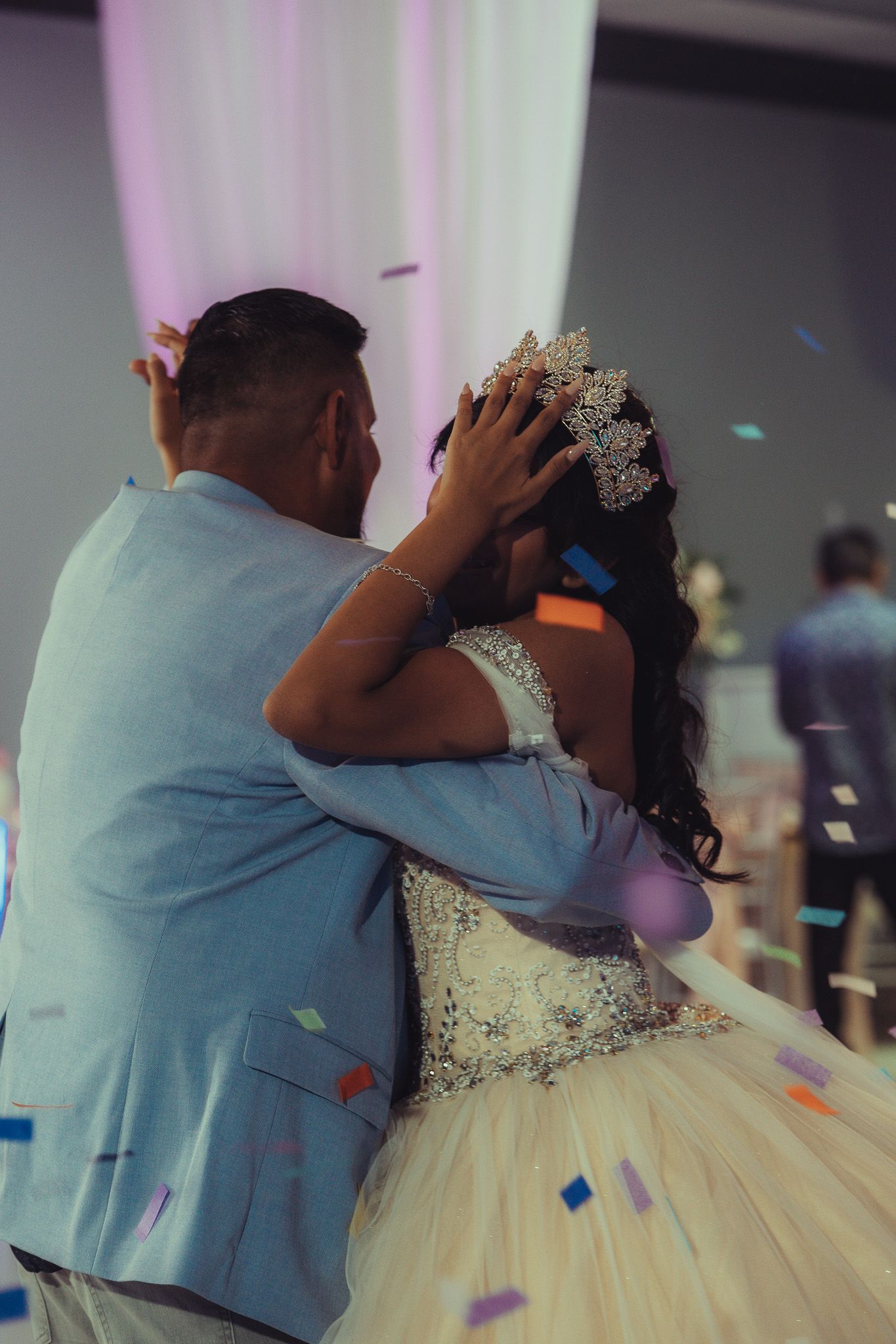 Couple sharing first dance at quinceañera celebration with colorful confetti falling around them.