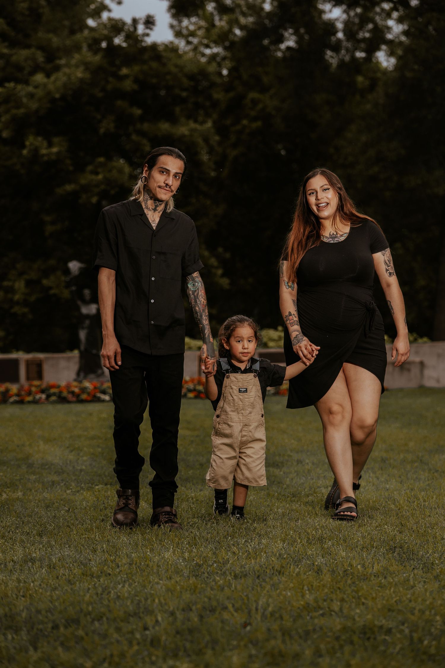 A family walks together on grass during a moody outdoor photoshoot at golden hour.