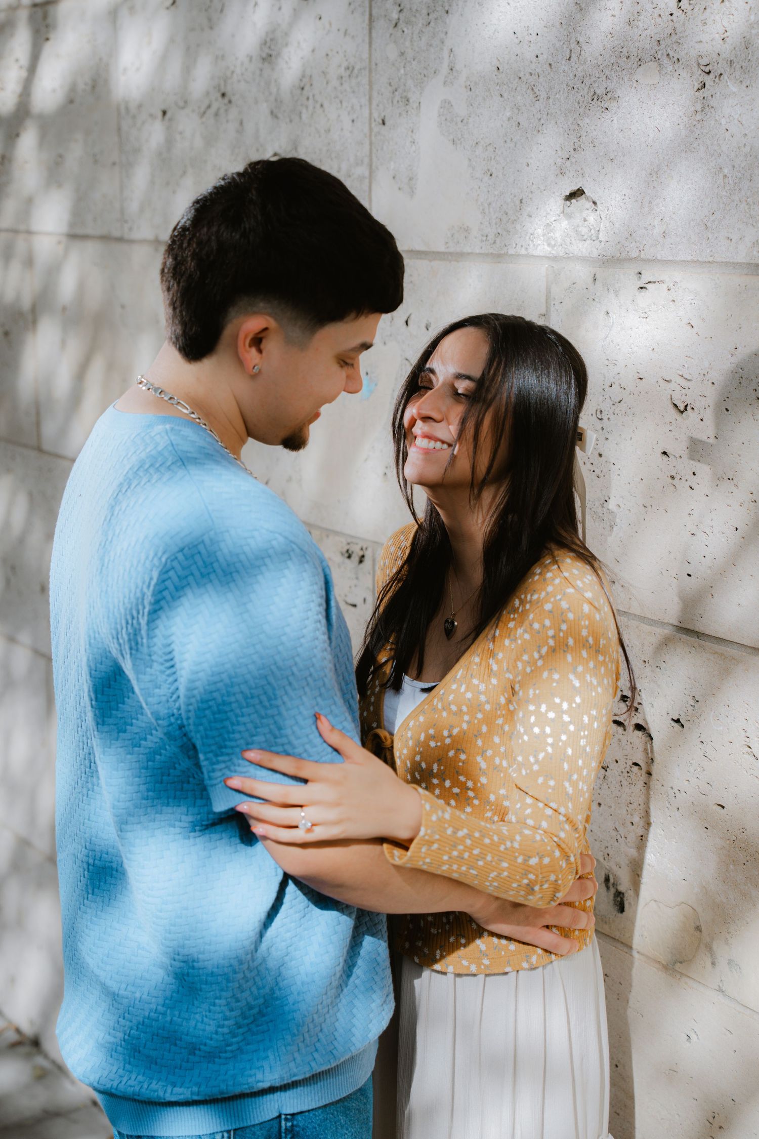 An intimate sequence showing a couple embracing against a textured concrete wall background.