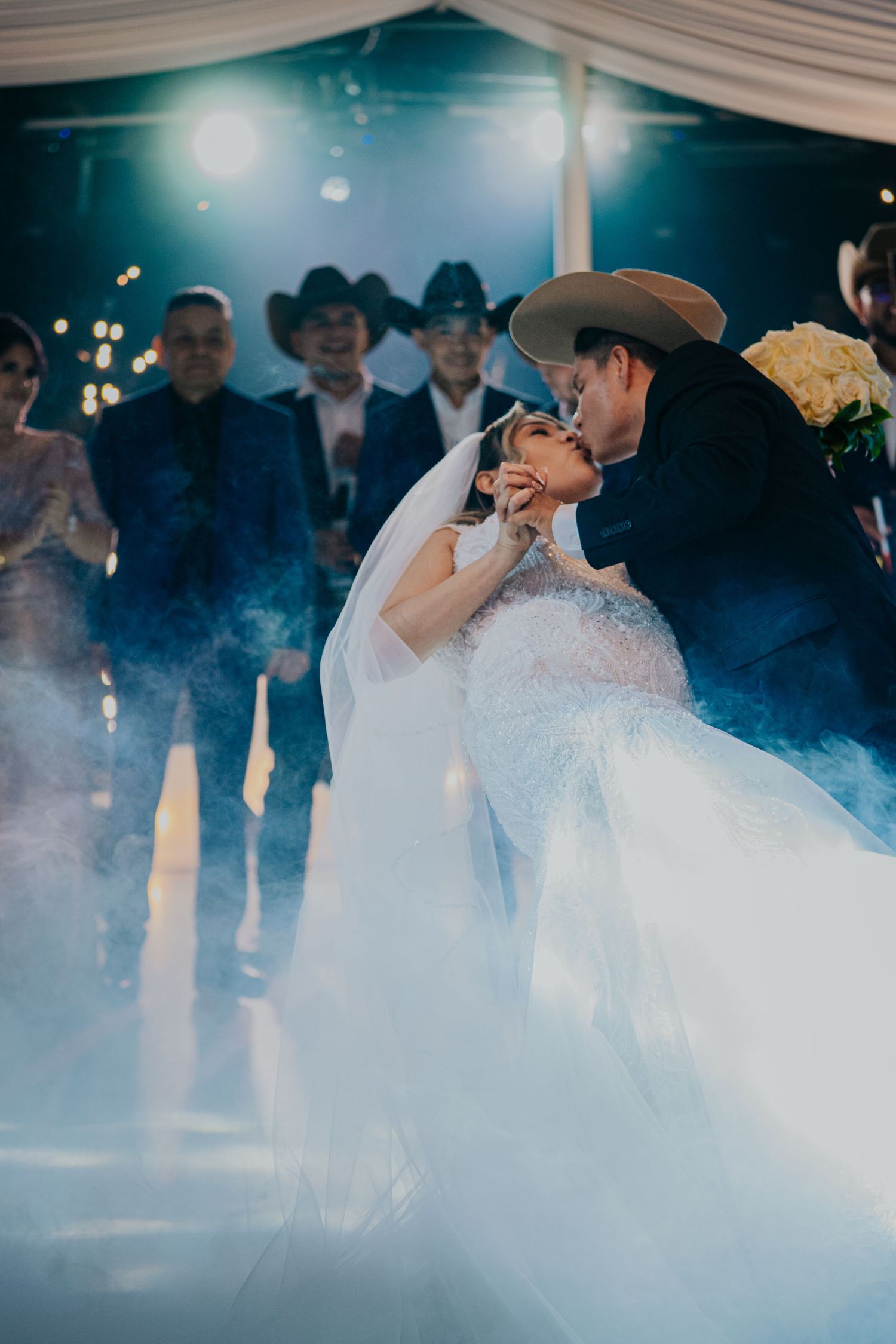 A couple shares a romantic first dance surrounded by atmospheric fog on their wedding day.