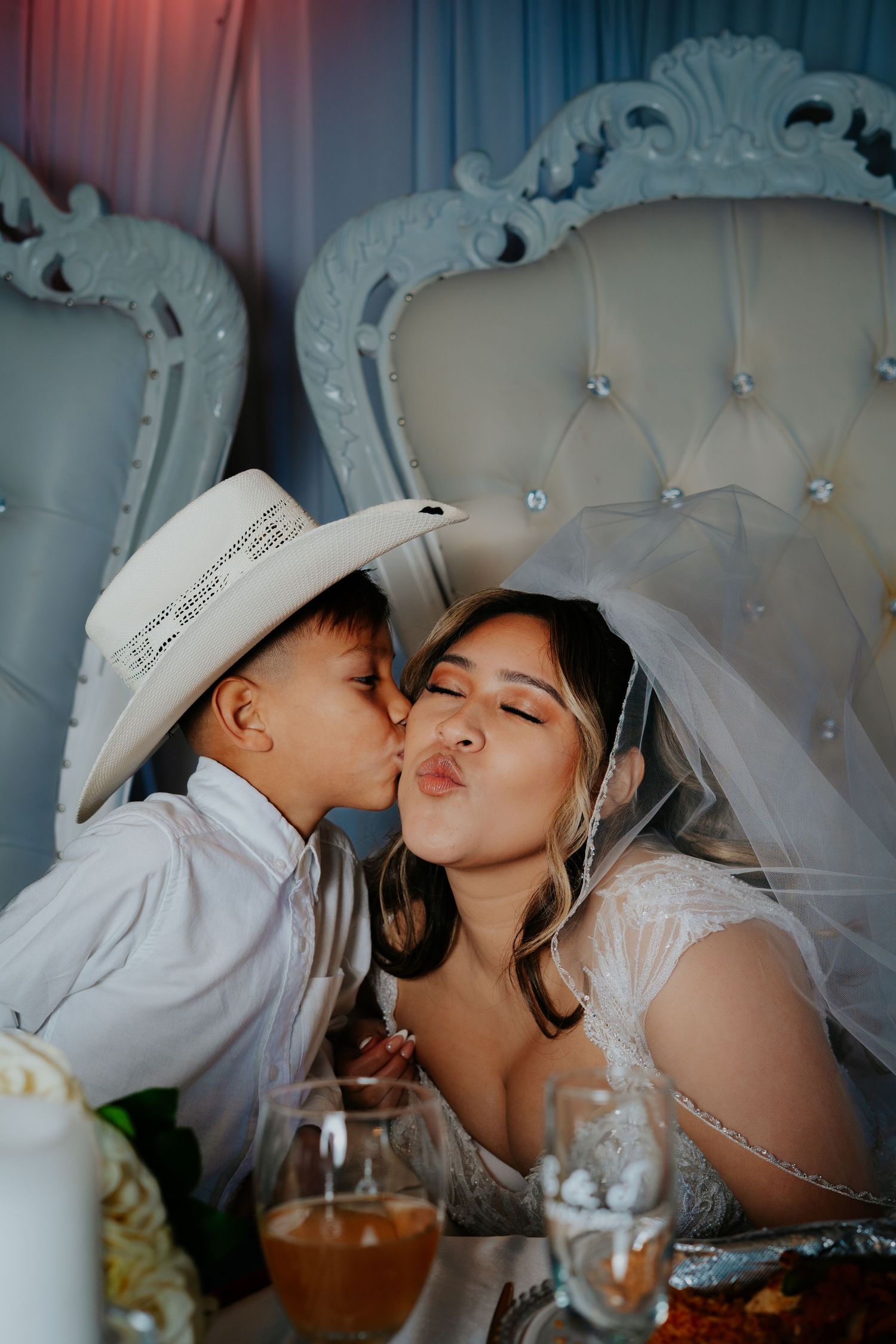 A tender moment shared between a bride and ring bearer at a wedding reception with elegant white decor.
