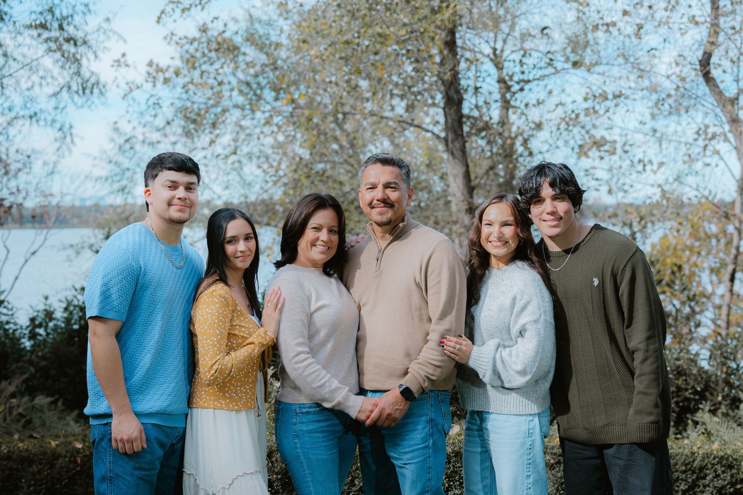 A multi-panel outdoor family photo session showing a group in coordinated blue and neutral outfits against a natural backdrop.