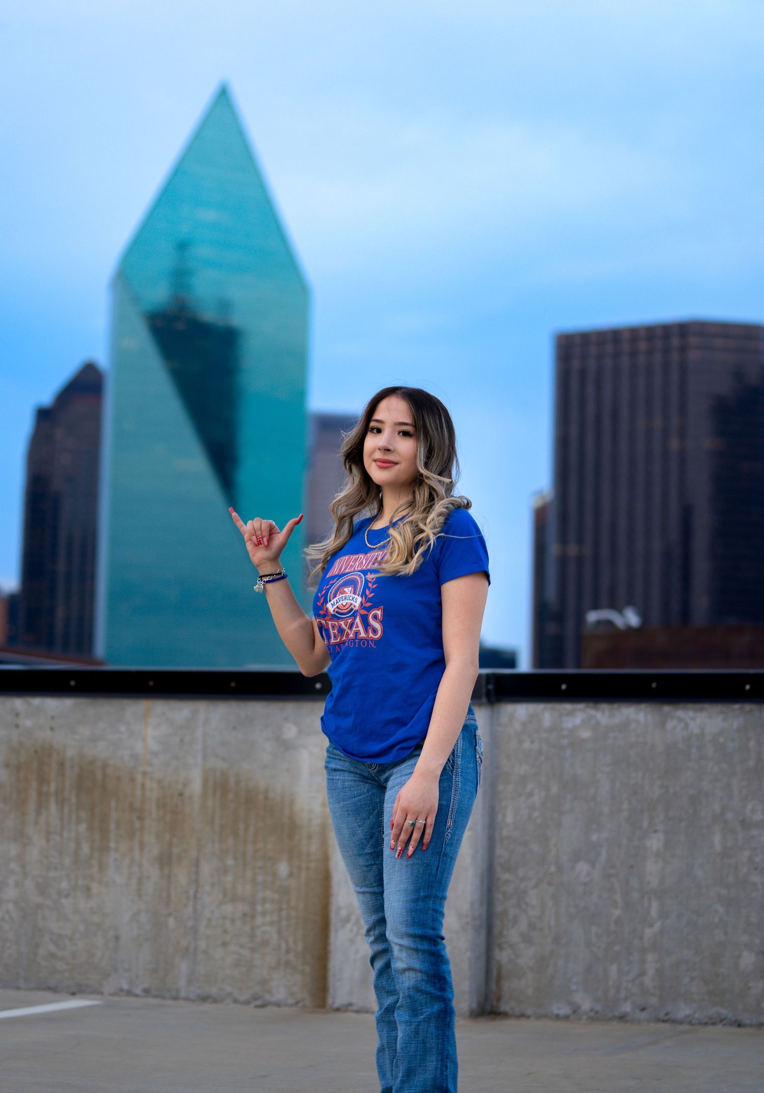 A person in blue shirt and jeans poses in front of a modern glass skyscraper cityscape in multiple candid shots.