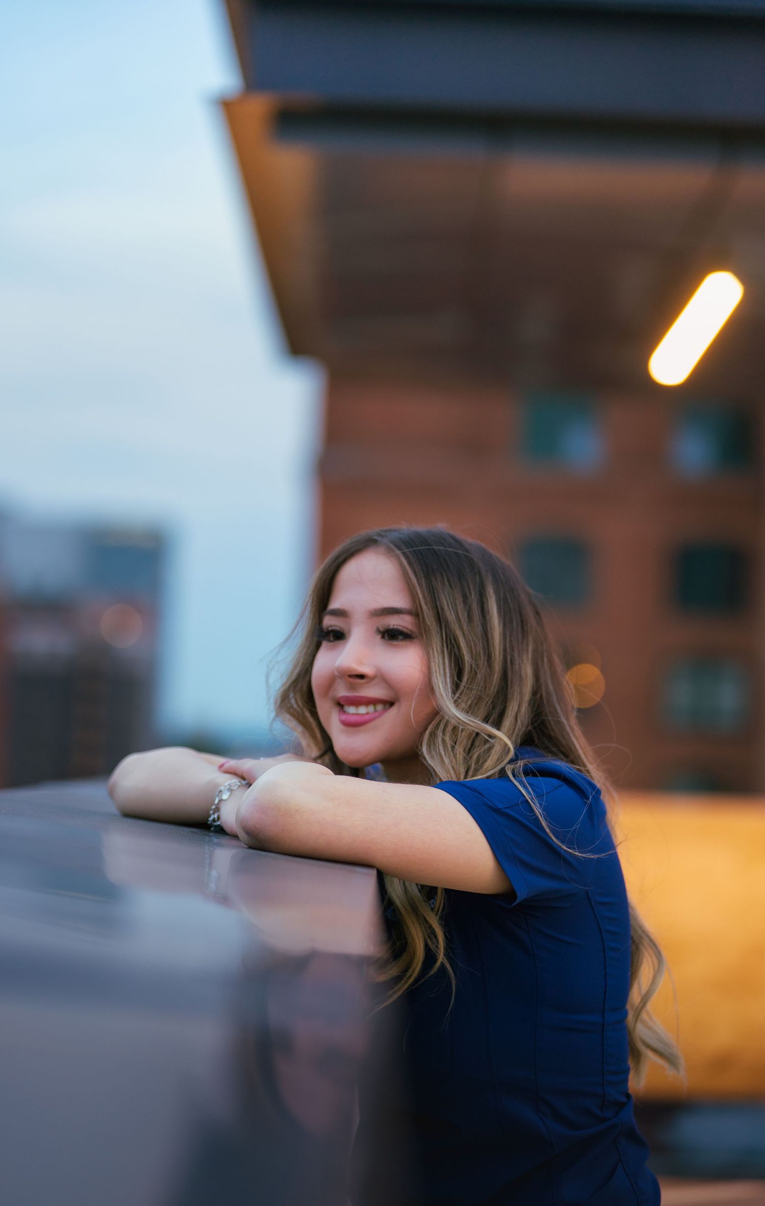 A sequence of photos showing a person in a navy blue top posing against an urban backdrop at sunset.