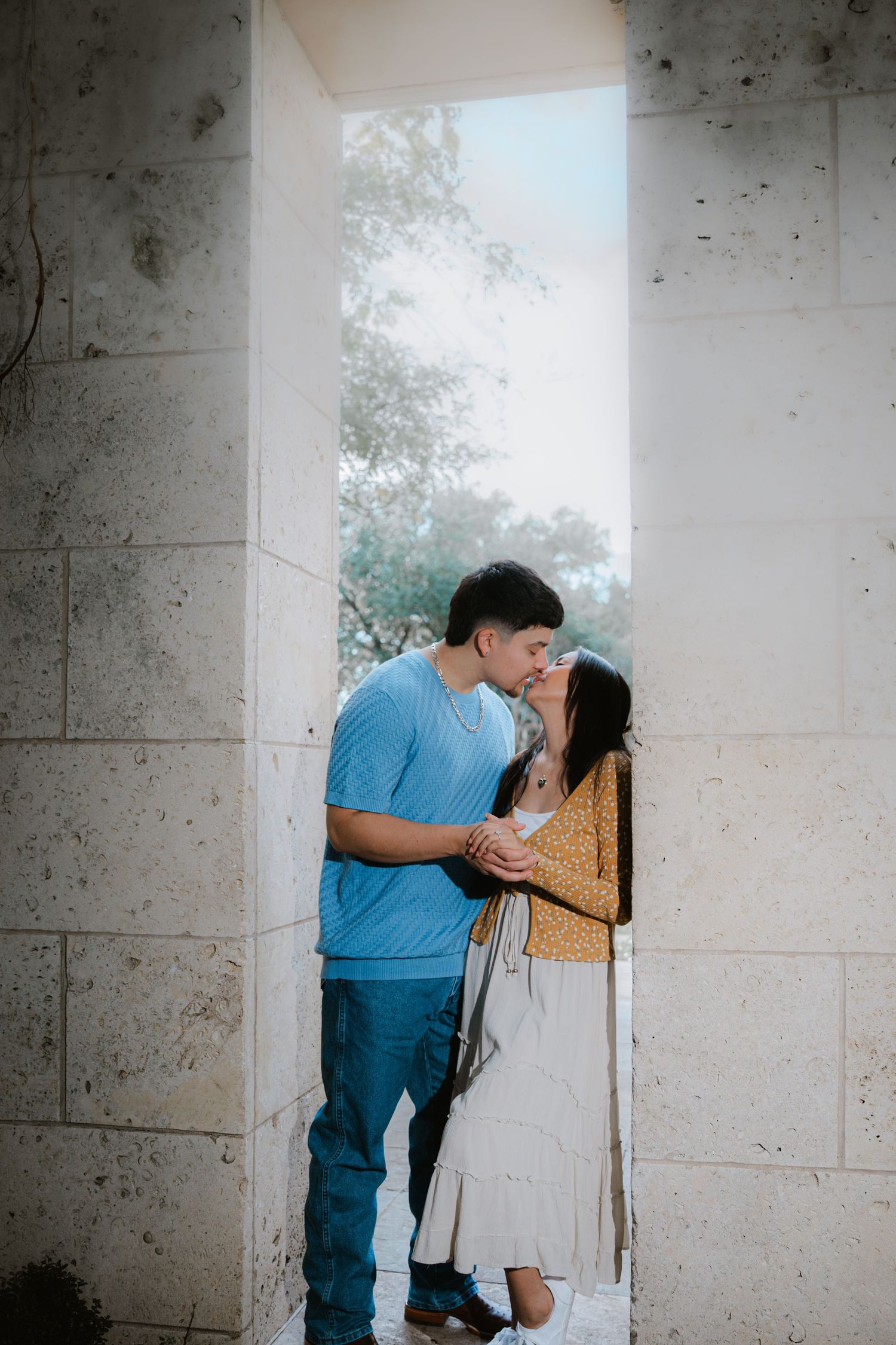 An intimate moment captured between two people in a concrete architectural setting.