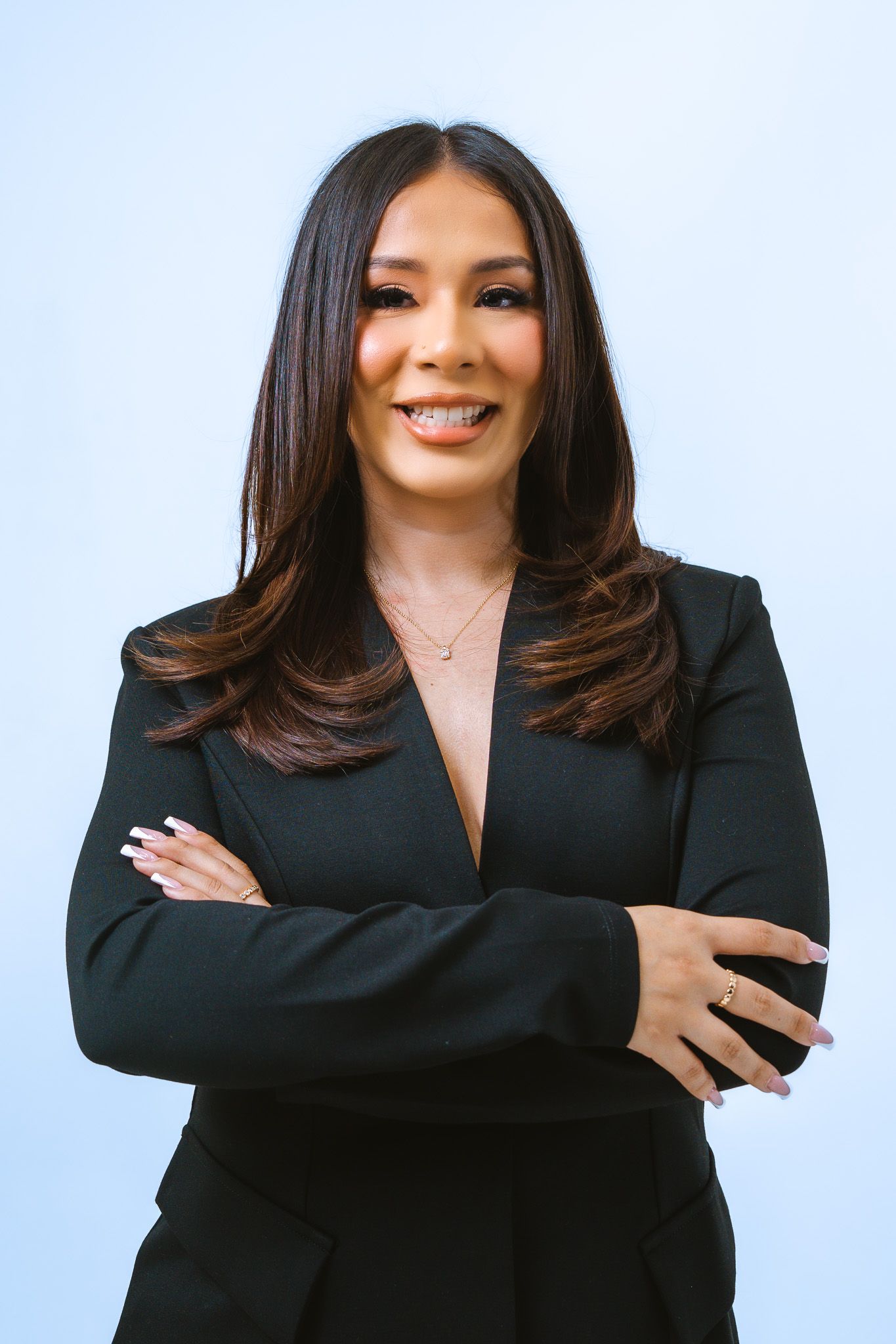 Professional portrait series showing person in black blazer against light blue background with warm expressions.