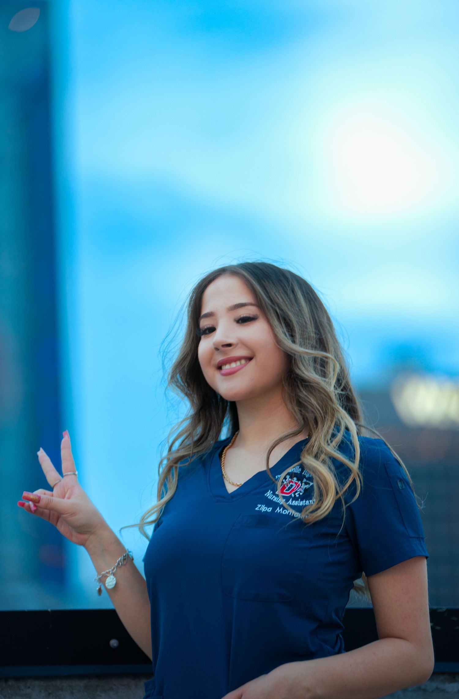 A person in a navy blue polo shirt poses expressively against a bright blue sky background.