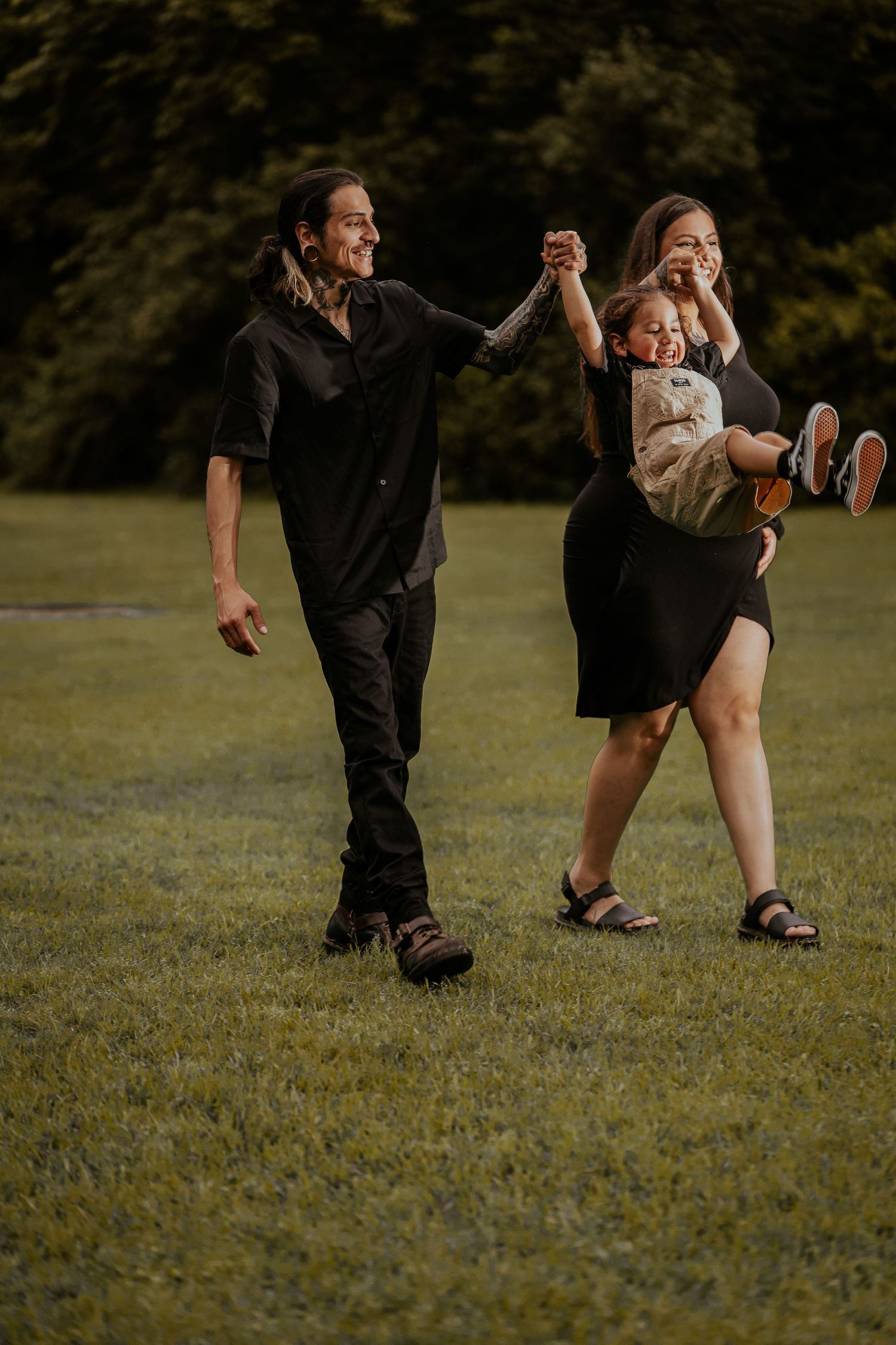 A playful family moment captured in a grassy field during sunset.