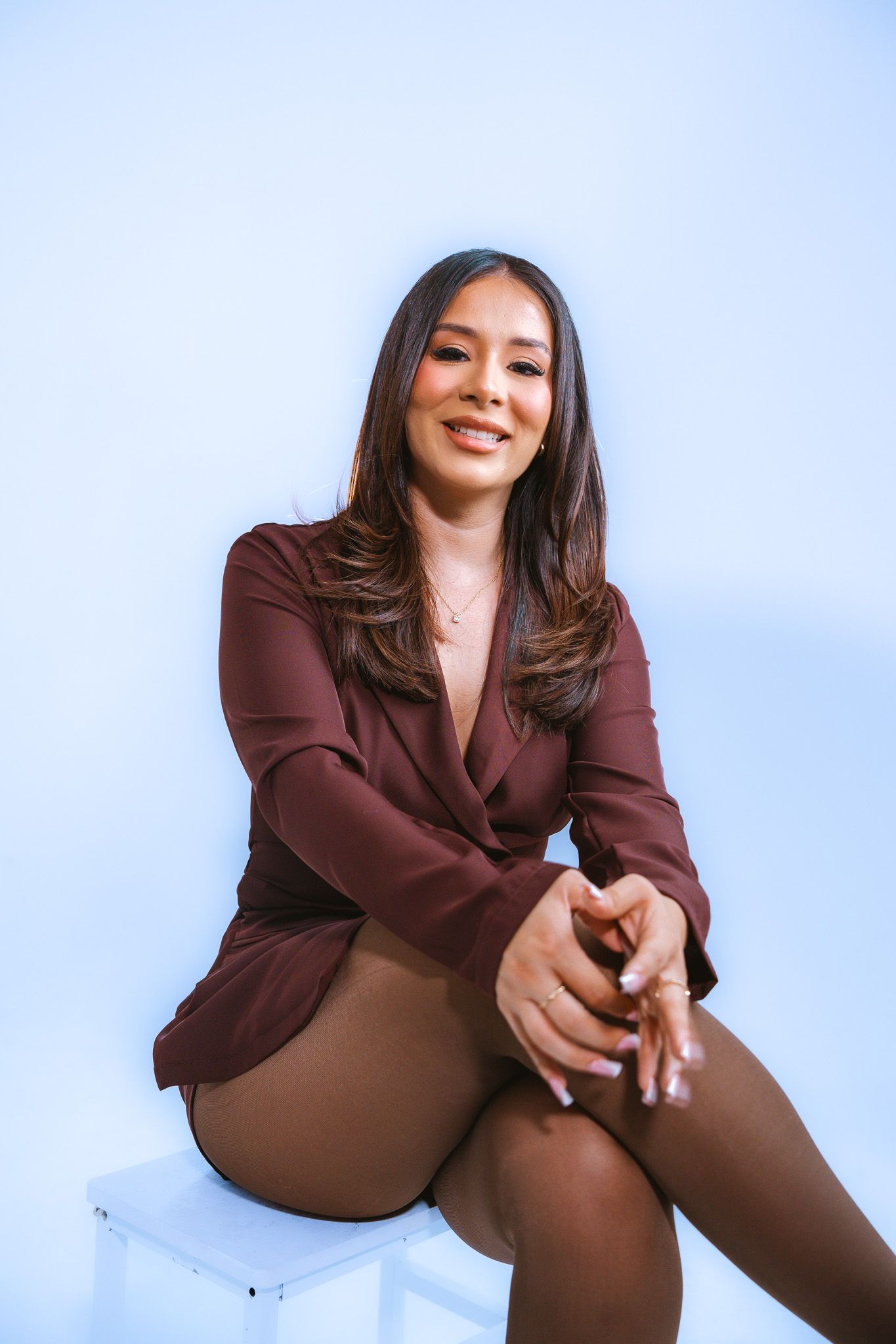 Casual lifestyle portraits featuring a burgundy blazer and relaxed sitting poses on a blue background.