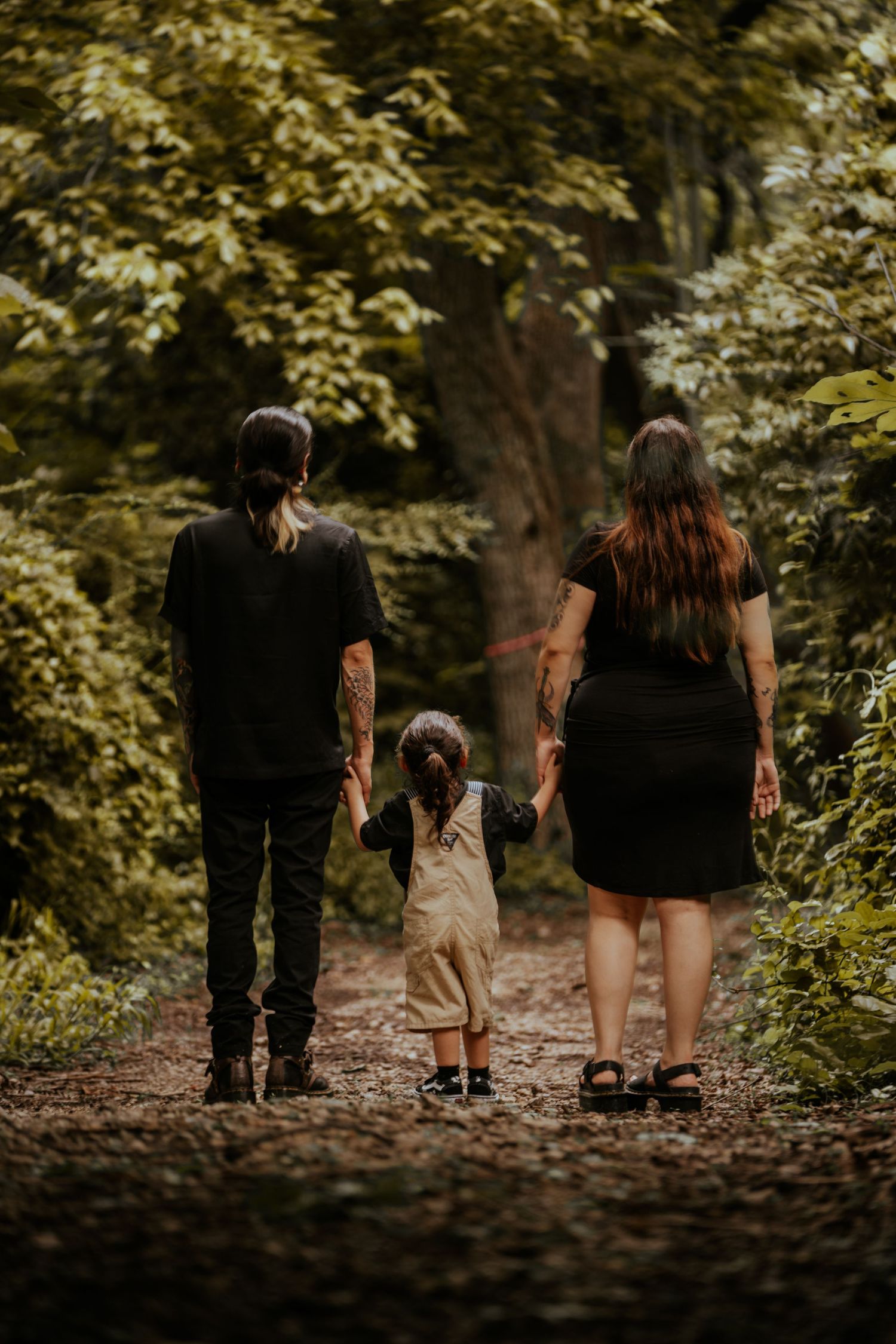 A family walks together along a tree-lined path during golden hour.