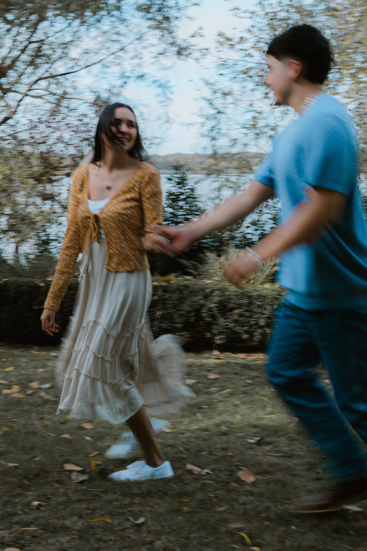 A couple in casual attire dancing and twirling together outdoors in a playful sequence of movements.