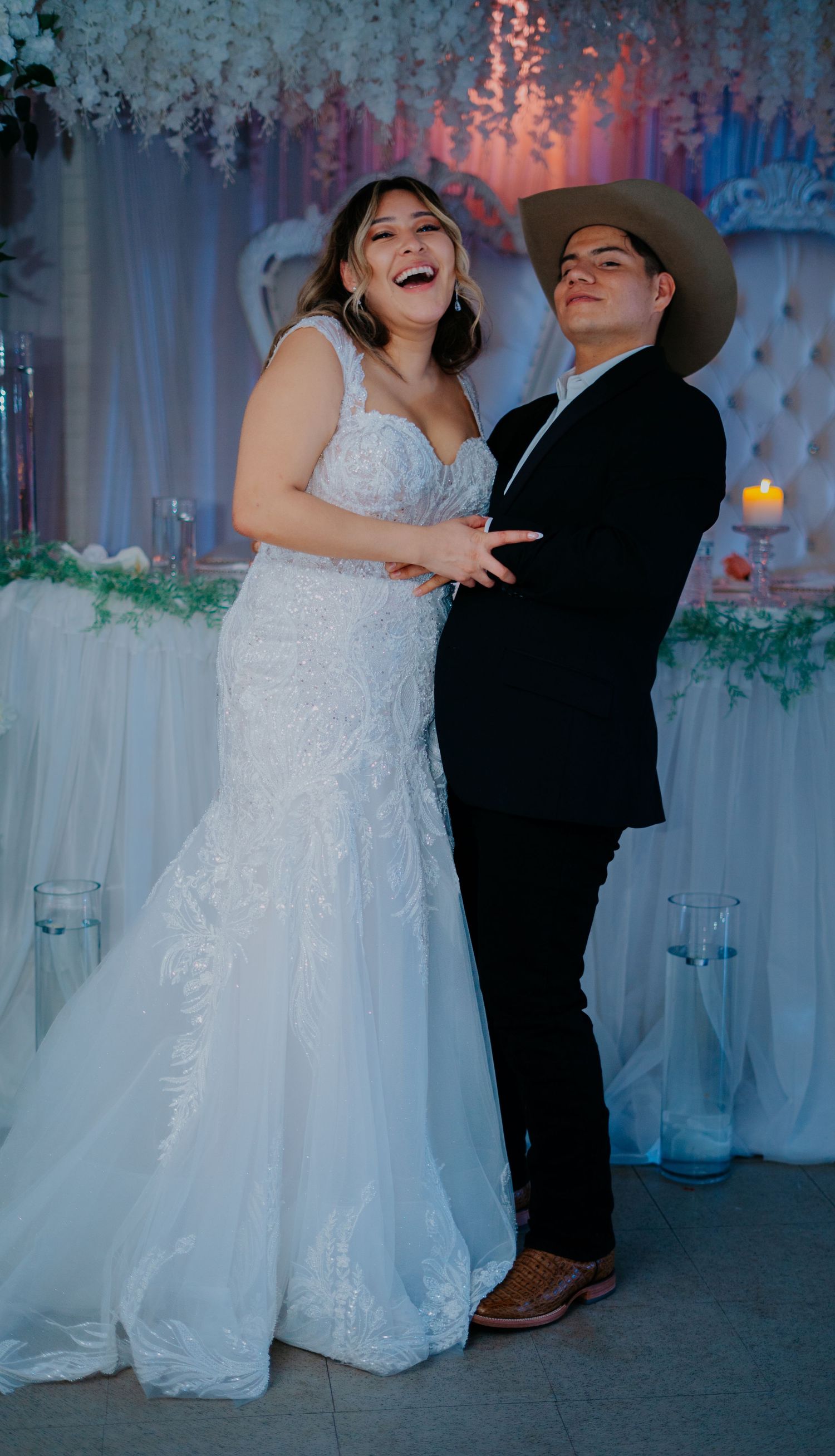 A couple shares a romantic dance at their wedding reception with colorful mood lighting creating a dreamy atmosphere.