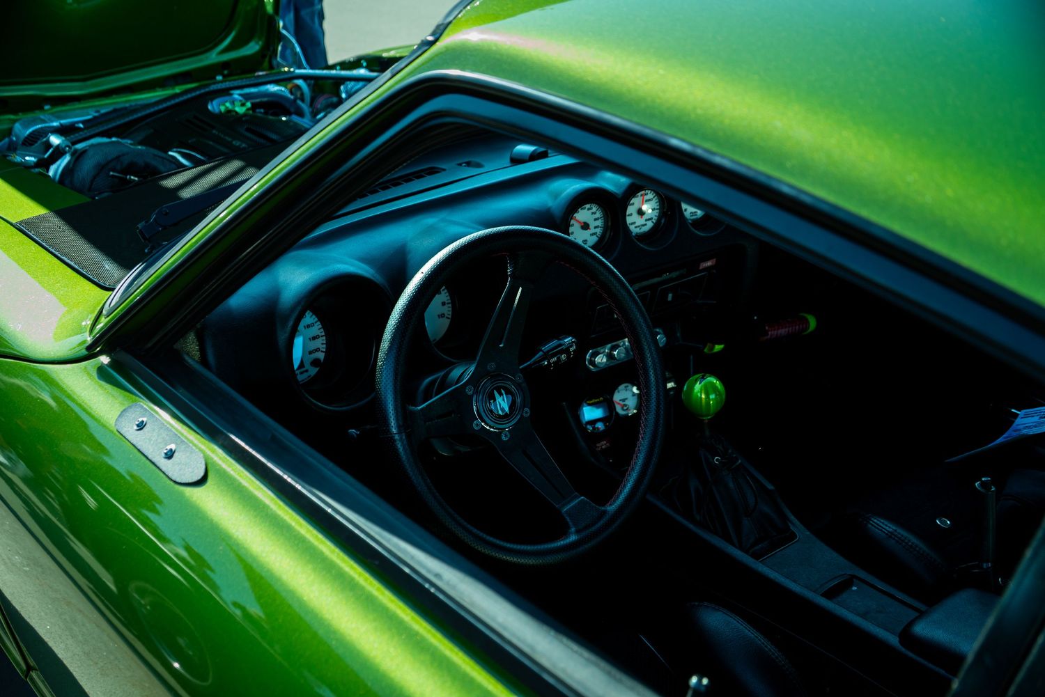 Interior and dashboard details of a green sports car in dramatic lighting.