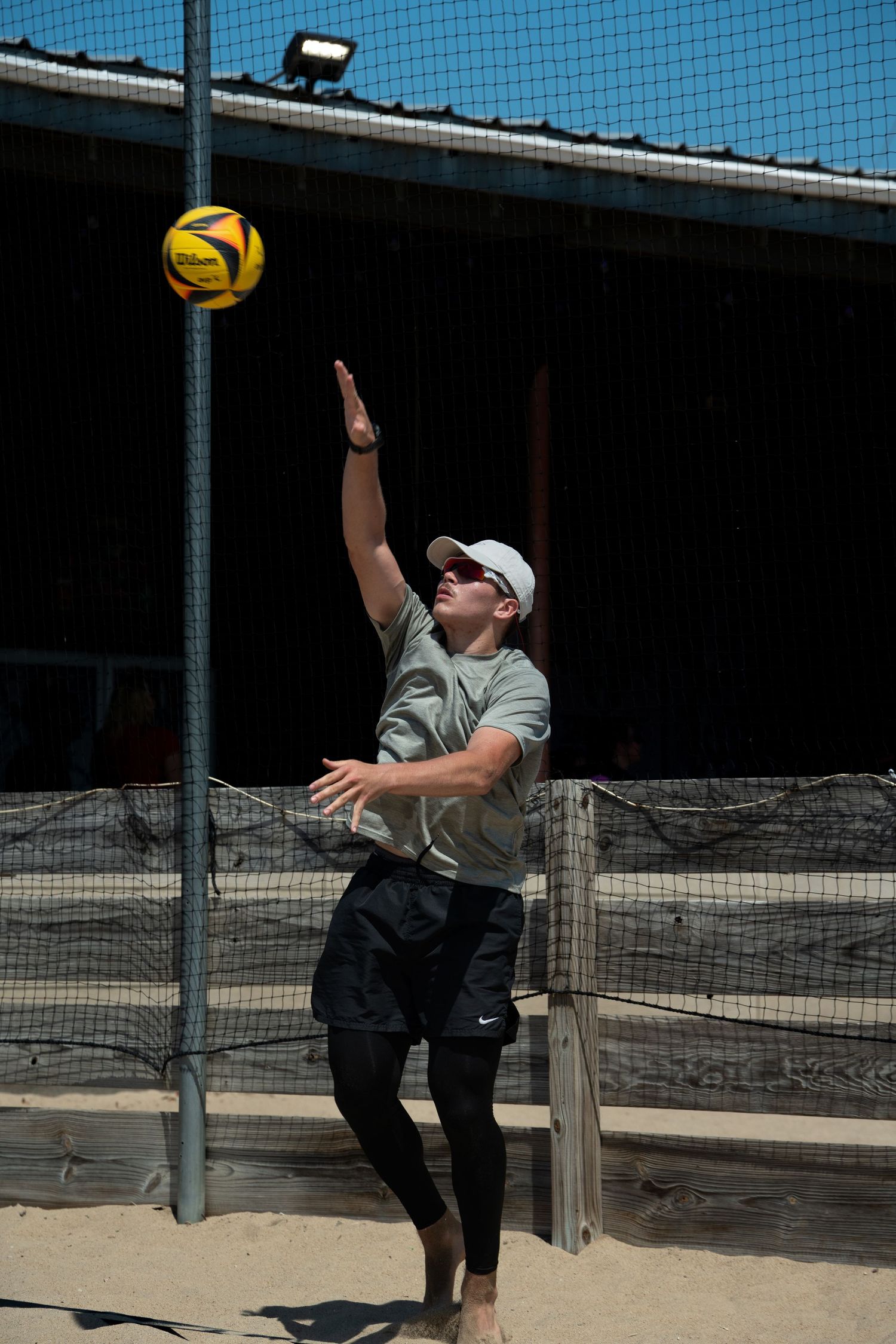 A volleyball player leaps to spike the ball during a beach game.