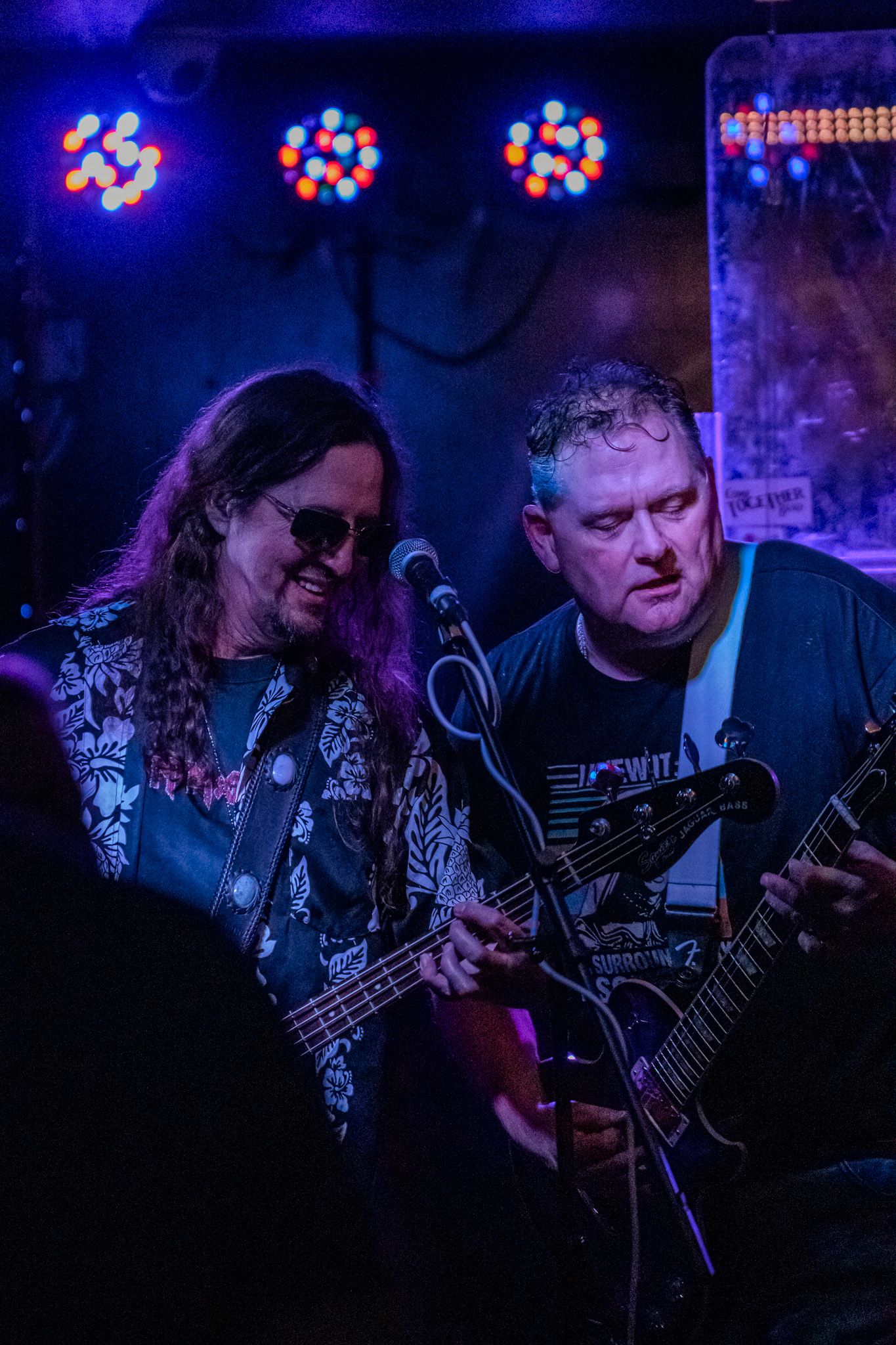 Band members play guitars during a live performance with colorful stage lighting.