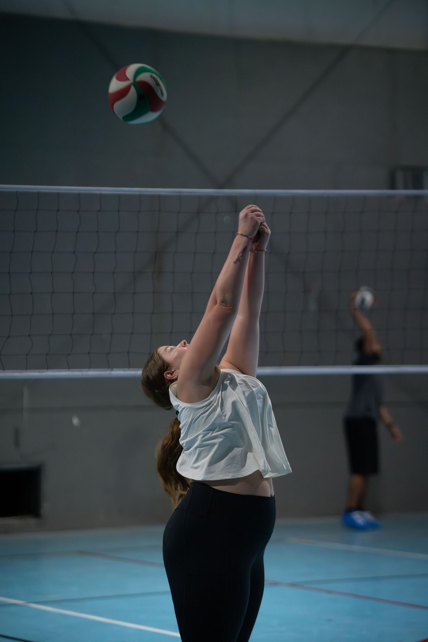 A player arches backwards to set a volleyball during an indoor game.