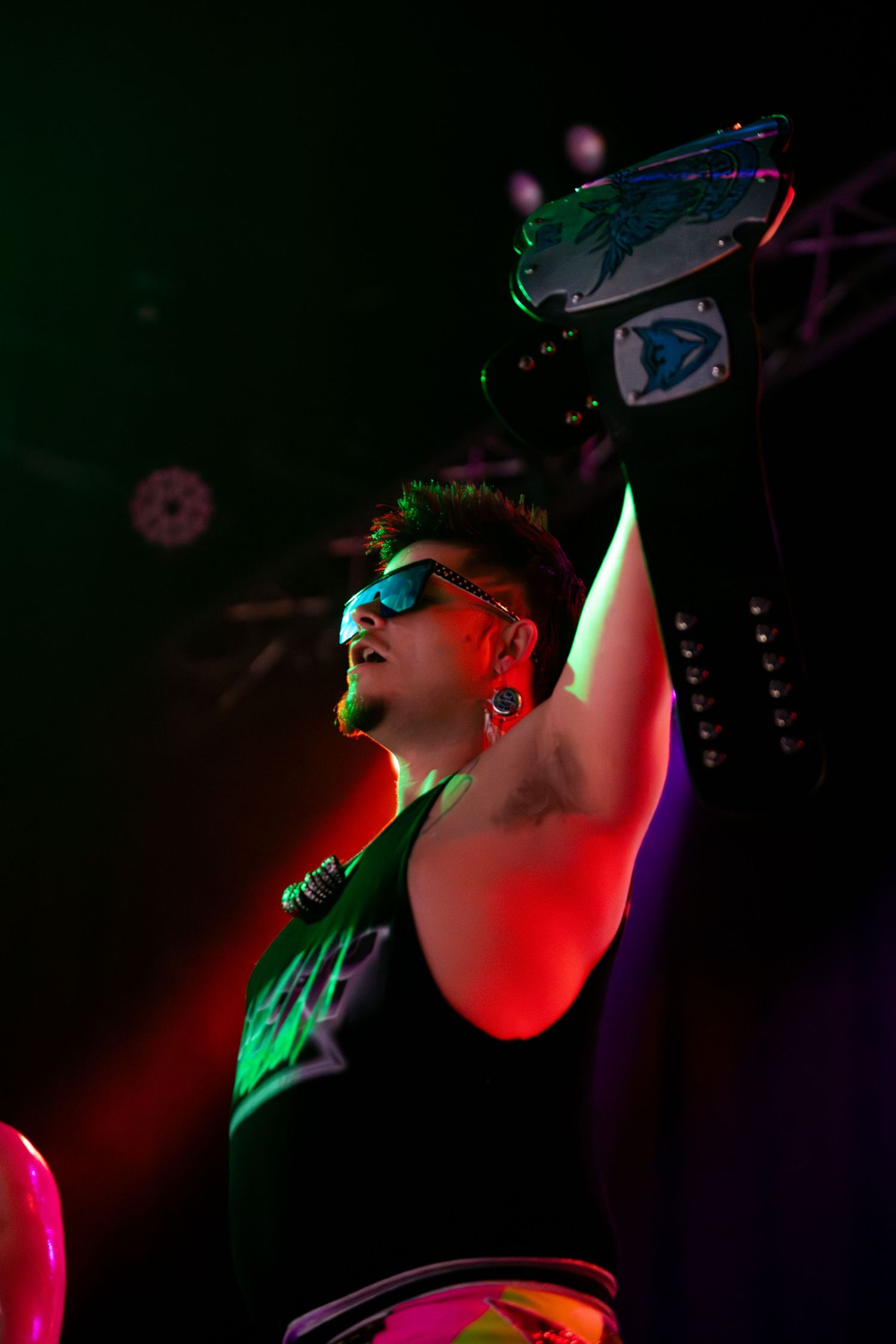 Concert performance with dramatic red and green lighting effects in a dark venue.
