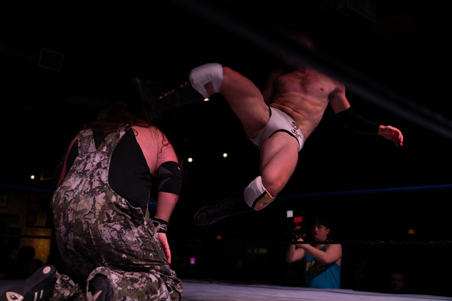 Wrestling sequence shows athletic moves being performed in dramatic lighting conditions.