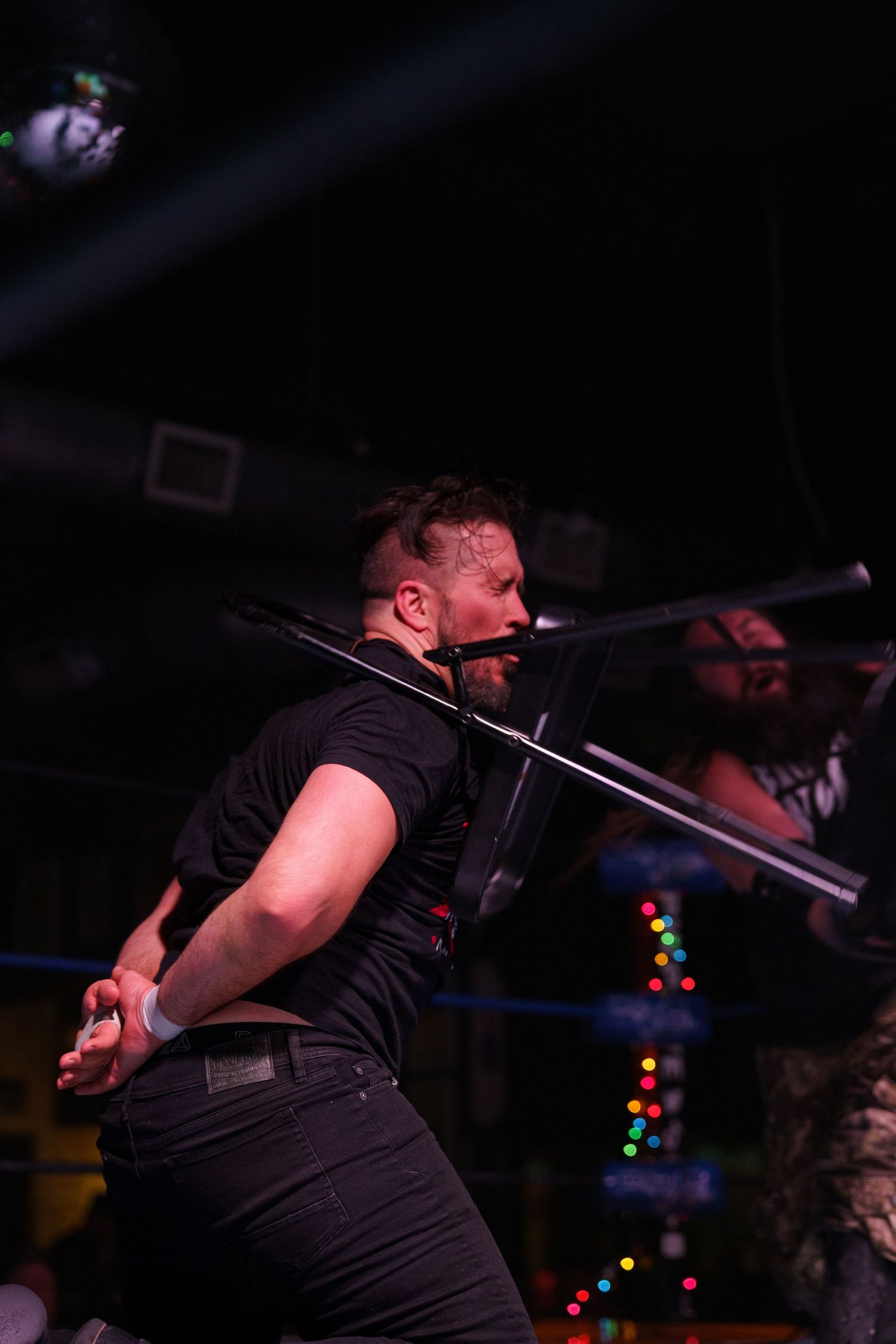 Performer in black shirt energetically take chair shot to the face