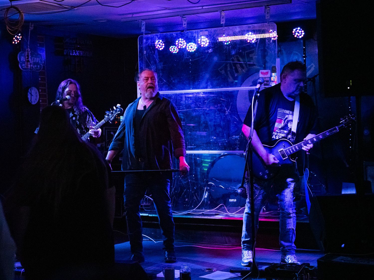 Wide shot of band performing on dimly lit stage with blue lighting effects.