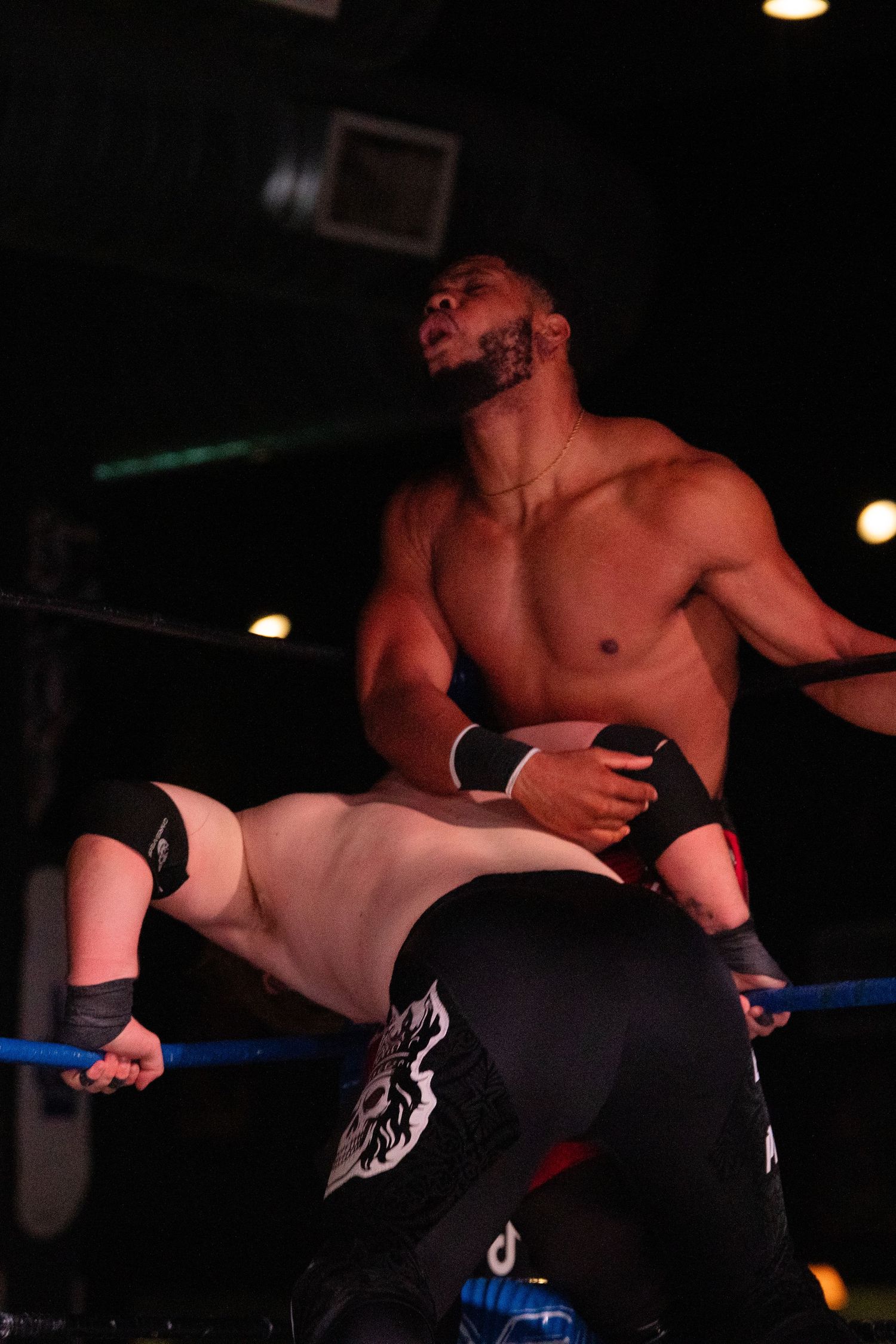 Wrestling match action shows a powerful grappling move being performed in the ring.