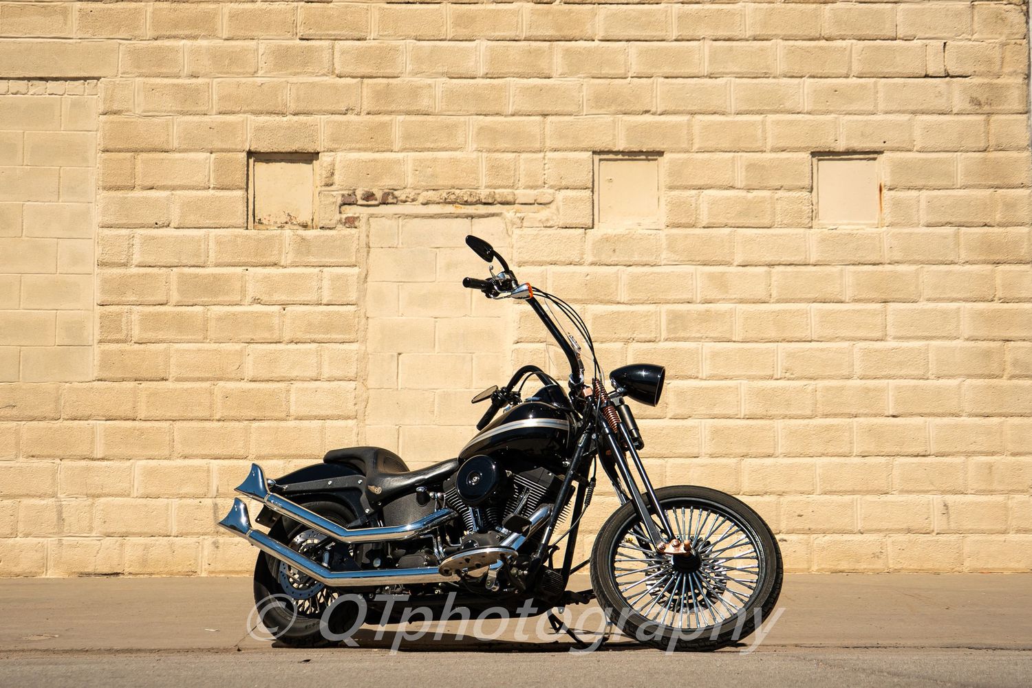 Custom motorcycle with chrome details photographed against a textured brick wall.